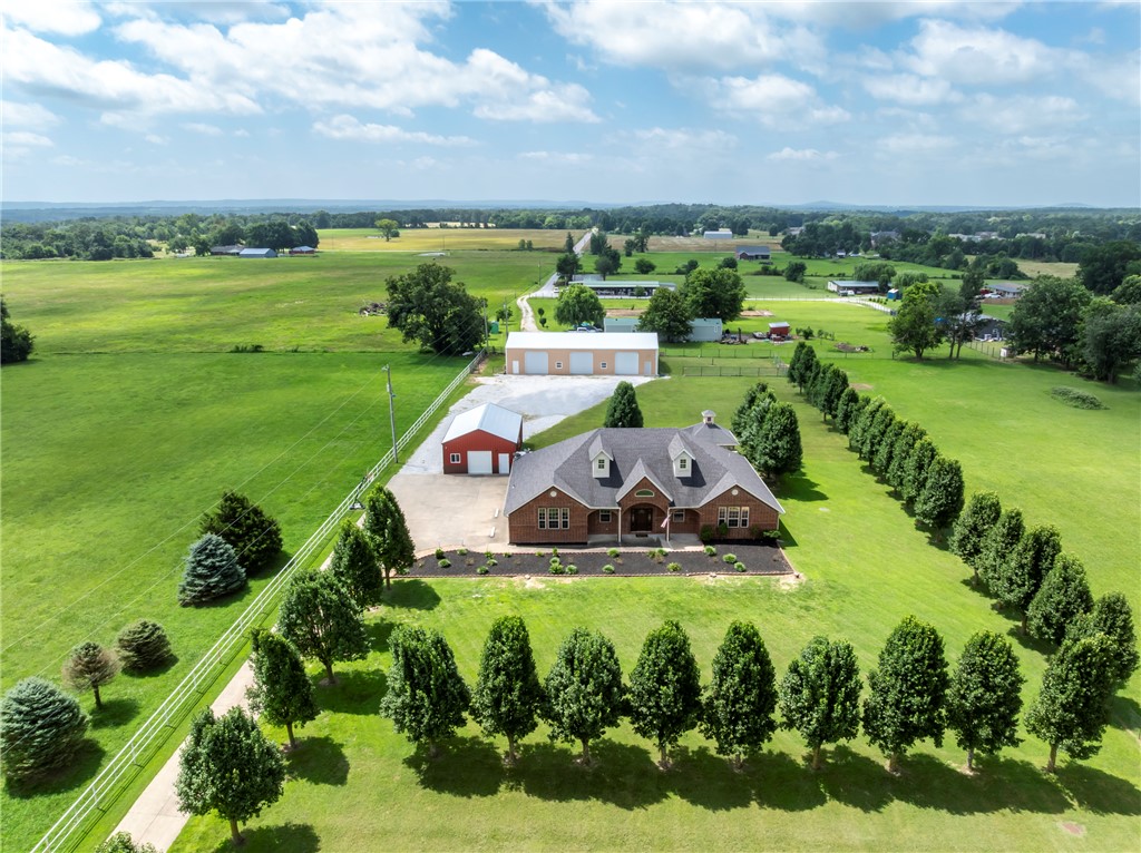 Welcome to your dream retreat on 3.09 acres accessed through a private gated entrance and a tree-lined driveway leading to the home. Inside, luxurious marble floors set the stage. The living area showcases a stacked stone fireplace with a pellet stove, and the gourmet kitchen features stainless appliances, a spacious island, and seamless dining flow. The primary suite pampers you with a spa-like shower and private office. Another flexible room offers a fifth bedroom option with a closet. Outside, unwind with your private hot tub beneath the pergola, with a hidden underground storm shelter nearby. Both the home and the 40X80 shop have security systems. The 3200 sq ft insulated shop includes electricity, cement floors, and 14ft garage doors.  Another 24X36 shop was used for entertaining with electricity and a large ceiling fan including epoxy floors! The entire home is completed with a salt water filtration system. This is country living with luxurious peace of mind! A must see! $6000 preferred lender credit offered.