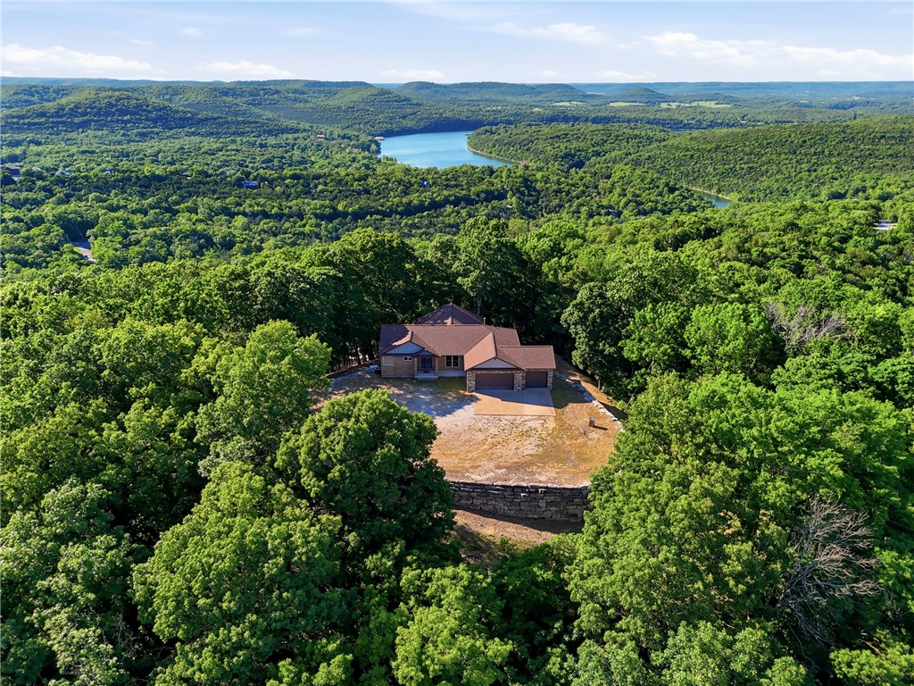 5-acre Mountaintop offers breathtaking year-round views of Table Rock and the Ozarks. With total privacy but located in Holiday Island close to the Marina and Golf Courses. Massive entertaining decks designed to soak in the beauty from sunrise to sunset. This custom-built home has over 4000 sq. ft. under roof. The main level is handicap accessible and features an open-concept layout with spacious living and kitchen areas, a designated dining room, and walls of windows that bring the outdoors in. Thoughtfully designed with 4 bedrooms, one currently serving as a dedicated office, while the remaining 3 bedrooms each offer private en suite baths with walk-in showers and generous walk-in closets, creating true primary-suite comfort for family or guests. A whole-home generator adds peace of mind, and all appliances convey at no cost to the buyer. The lower level is ready for the new owner’s vision with endless possibilities for additional living space, guest quarters, or workshop.