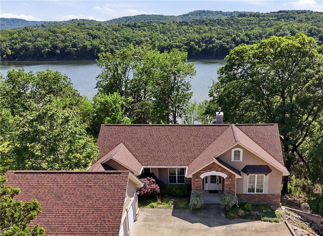 No detail has been spared in this stunning riverfront home, which offers breathtaking views of the White River. You'll appreciate the main-floor living with an open floor plan that offers river views from every room. The gourmet kitchen features quartz counters, custom cabinets and stainless steel appliances. The living room has vaulted ceilings and a gas-log fireplace. Wake up to river views in the ensuite bedroom, which has sliding doors to a covered deck. His and her closets are conveniently located in the hallway to the bath, which offers a tiled shower, soaking tub, separate vanities, and a water closet. The lower level includes a spacious family room, two ensuite guest bedrooms, and a bonus room that could serve as a fourth bedroom or office. A covered deck stretches across the back, leading to steps to a hot tub and fire pit. Enjoy access to two golf courses, clubhouse, a swimming pool, tennis courts, pickleball, and more. The home is also close to Roaring River State Park and Dogwood Canyon Nature Park.
