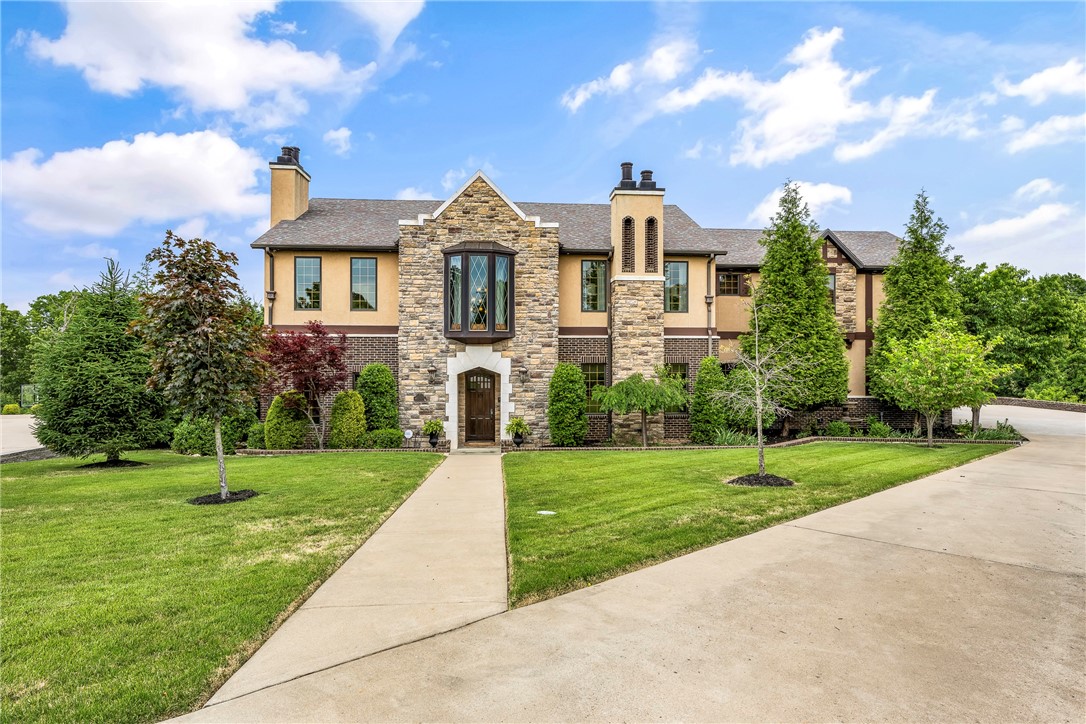 Gorgeous 5250 sq ft custom Tudor home full of old world charm with modern upscale amenities. Soaring 22' ceiling in kitchen, breakfast, and family room. 6 x 9 island with copper apron sink and 2 dishwashers. 6-burner gas stove with griddle. Breathtaking woodwork and details throughout. Multiple outdoor entertaining options overlooking a stunning saltwater pool with copper waterfalls. Outdoor kitchen, outdoor shower. Every bedroom has a private bath. Home was featured on HGTV. All of this sitting on gorgeous 1.5 acres of secluded property, all in the convenience of Fayetteville, close to I-49, U of A, the NWA Mall area, and more. Drapes in the great room and primary bedroom do not convey.