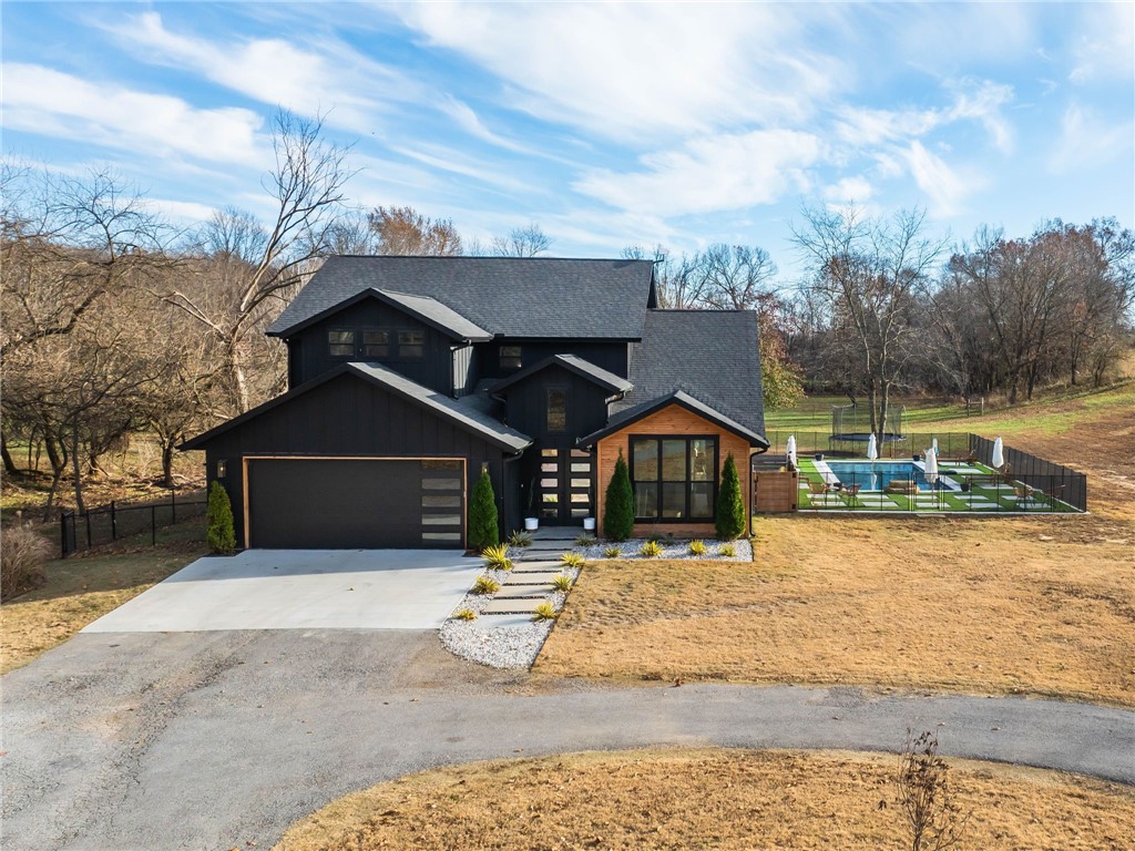 Experience the perfect blend of luxury, comfort, and sustainability in this custom built estate. Located within the acclaimed Bentonville School District, this extraordinary property offers limitless possibilities for an enriching lifestyle. Enjoy rural charm with access to premium education and nature's beauty. This home features four spacious bedrooms and 3.5 lavish bathrooms, showcasing modern elegance and style. This estate sits on 10-acres, ideal for outdoor recreation and self-sufficient living. Inside, an inviting open floor plan seamlessly integrates an airy living room and gourmet kitchen, perfect for culinary enthusiasts and entertaining. Step outside to your private haven, featuring a stunning 14x34 gunite pool surrounded by a plush turf patio. The estate is equipped for livestock lovers with a 30x40 shop, two fenced pastures, and a delightful chicken coop. Embrace eco-friendly living with a fully operational solar system for energy efficiency. A two-car garage adds to daily convenience.