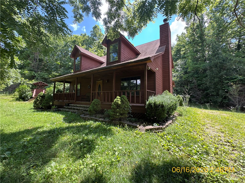 Charming two-story cabin/farmhouse on 5.01 wooded acres offering privacy and country living. This 4-bedroom, 2-bath home features an open-concept great room with a stunning stone fireplace and wood-burning stove insert, hardwood floors on the main level, and a spacious kitchen with wood cabinetry, breakfast bar, and appliances. The master bath includes a garden tub and separate shower. Enjoy the outdoors from the covered wraparound porch, screened rear porch, and gazebo deck. Additional highlights include a detached shop/garage with electric and concrete floor, well house, central heat and air, and a private gravel drive. Bank-owned/REO property being sold AS-IS; some interior finishing needed. Buyer to verify all information including square footage, acreage, and schools. Great opportunity for buyers seeking acreage and a country retreat.