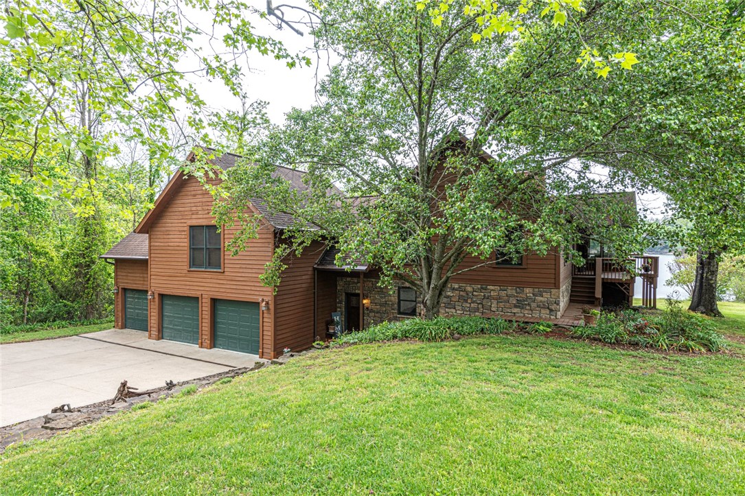 LAKE FRONT/LAKE VIEW HOME! This GORGEOUS 3bd/3 ba cedar lodge w/ full cove & private boat dock is an oasis on 1.617 Acres +/-! Full remodel in 2006! Fresh interior paint throughout! Head inside to the 1st flr w/ workshop/craft room, gym space, storage, & a large bonus rm w/ LVP flooring, 2nd living space, wood burning FP, flex space, & wetbar! 2nd flr (Main) enjoy an open concept feat: Oak hardwood flooring, vaulted ceilings w/ wood beam & plank details, stone wood burning FP, 2 floor-to-ceiling walls of windows, & STUNNING views! Office space off the entry! Relax and rejuvenate in the primary bedroom w/ two walk-in closets with Laundry rm, & private bathroom w/ double sink vanity, jacuzzi tub, and walk-in shower! Plus two additional bedrooms and additional full bathroom! Head out back to the wrap-around deck feat 180º views of Beaver Lake! Plus easy access to the private boat dock! With 1.617 Acres +/- you'll have plenty of space! More Feat: Wired for Sound, Security System Conveys, Intercom System, and 4 Zone AC!
