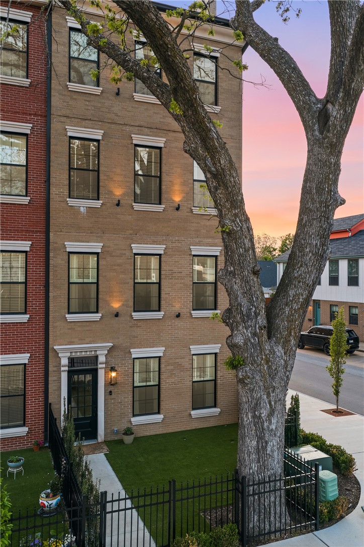 Oak One's flagship — a four-story corner brownstone with 3,042 SF, five bedrooms plus a top-floor bonus room, 4.5 baths, and a private fenced courtyard.
1,200 pounds of hand-set cast stone frame the entry with dentil molding, fluted pilasters, and scroll corbels. Chevron hardwood runs throughout. The main level lives open: chef's kitchen with quartz waterfall island, GE Cafe double-oven range, pot filler, and a great room anchored by a 60-inch fireplace.
The primary suite is a retreat — fireplace, walk-in closet, spa-like bathroom with floating vanity, backlit LED mirror, electric towel rack, and Hansgrohe rain shower.
The fourth floor is the showstopper: a family room beneath Velux skylights with two of Bentonville's most iconic views — the Ledger to the east, the water tower to the north. Sunrise coffee at one window, sunset wine at the other.
Walk to the Square. Adjacent to Gilmore Park and the new STEM university, minutes from Crystal Bridges, the Momentary, and Walmart Home Office.