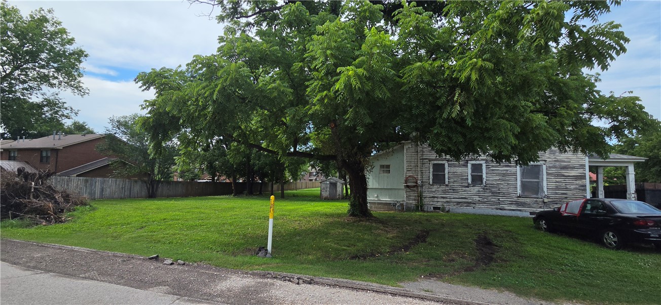 Sold as is - the buyer accepts the property in its current condition with all faults and waives the right to demand repairs or warranties from the seller. Cash Offers only - will not finance as plumbing is not working in the house and there are no appliances.  Discover a piece of Siloam Springs history.  This home was built in the early 20th century and is still standing proudly on the corner of Helena and N. Mt. Olive on a lovely, level .25 acre lot. New roof in 2026. It can be a beauty again with someone who wants to polish those hardwood floors and staircase and do all the updates needed to make it beautiful again. .  There is water at the house but drain in kitchen is leaking and other plumbing conditions are unknown. The broken windows are being replaced.