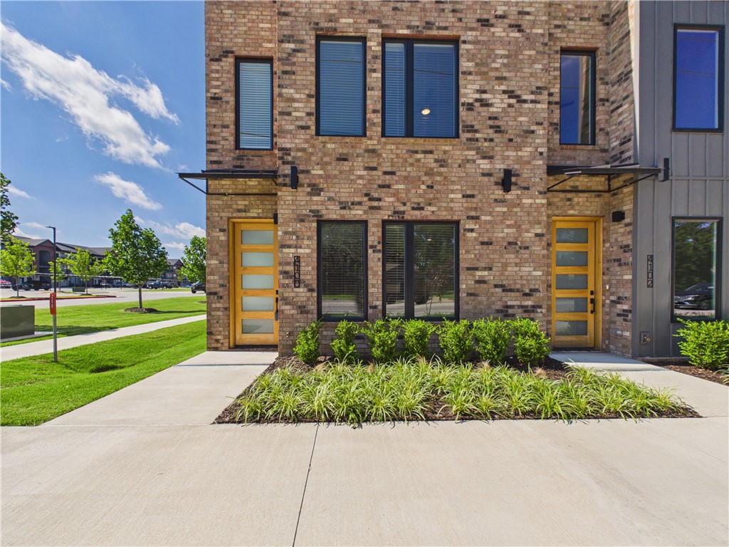Enter the front door and forget your worries outside--literally. This luxury townhome is built to enjoy life and the convenience both of location and amenities. Never worry about the lawn/landscaping, or the honey-do lists...exterior maintenance is all covered! So use that extra time to walk over and enjoy a movie night at the theater, or stroll to some of the nearby restaurants for dinner. Swing through for coffee on your way out to hit the trail access across the street.  This open floor plan is one of two END units available! The extra windows bring in loads of natural light. Executed with top-notch finishes this sophisticated townhome is ready for you to bring your vibe and enjoy the ease of being in the middle of everything Northwest Arkansas has to offer. Three spacious bedrooms plus an office/flex space, two and a half baths plus an oversized 2 car garage with EV charging ready to go.