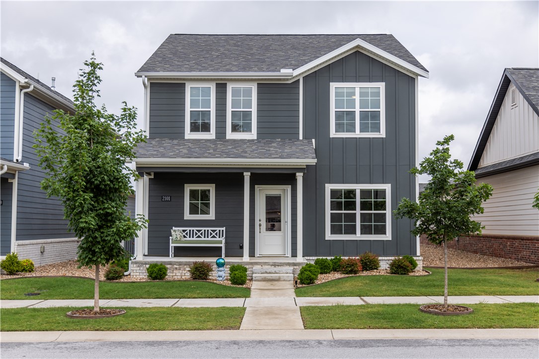 Ideally situated 2 miles from the Bentonville Square, this amazing property is easy living and low maintenance. Lawn mowing and edging is included in the POA dues as well as manicured common areas, access to an event pavilion, pickle and bocce ball courts, and a gated dog park.  This beautiful home is 3 years new and offers 1963 sf, 3 bedrooms AND a dedicated office, & 3 bathrooms. The owner has added a beautiful synthetic deck, a closed in sunroom between the home & garage with 2 oversized sliding glass doors and epoxy flooring. Both sides of home have pebble rock, sprinkler system in ground, a water filtration system, extended space in the garage, and add'l storage under the stairs.  Refrigerator, washer, dryer, and work bench convey with sale.  The primary bedroom and ensuite are oversized and tastefully done with a separate tub and shower, private commode, and a huge walk-in closet. Range in kitchen as well as fireplace are electric but also plumbed for gas. Seller prefers to not close until end of July.