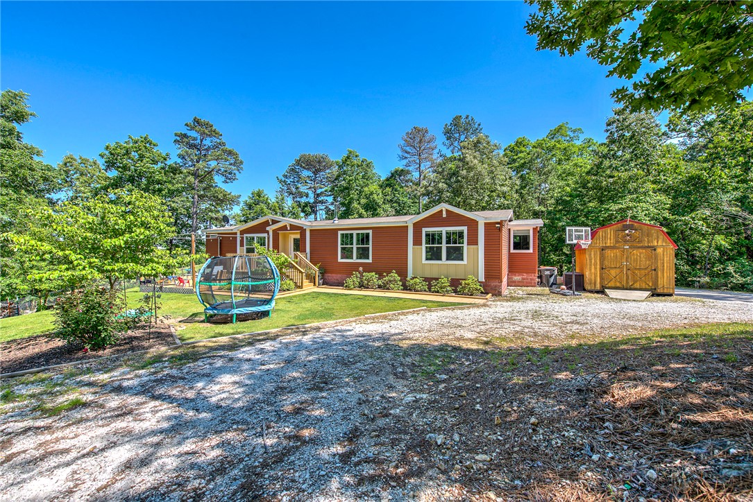 Nestled on 1.83 acres Near Beaver Lake and State Park.  Tranquil setting and surrounded by pasture and woods lands.  Open floor plan with huge kitchen and family room. Every window has an incredible view.   This property supports gardening, animals, and everyday outdoor living. Enjoy blackberry patches, strawberries, apple trees, and wild blueberries, plus a fenced, planted garden and cedar raised beds. A horse shelter and small animal pasture add flexibility, along with nature trails, a large treehouse, and forest play area. Relax on the covered back deck or front deck. Outbuildings offer workspace and storage. Solar panels and a newer storm shelter add value. No HOA.
