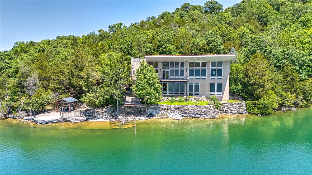 Unparalleled lake views. Private boat launch. Boat slip on community dock. Gorgeous home. This one-of-a-kind lakefront retreat on 1.42 acres along Beaver Lake checks ALL of the boxes! With nearly 3,900 sq ft, this custom-built home features gorgeous Austin Stone, 3 bedrooms, 4 baths, and soaring 11-ft ceilings on both levels, as well as unfinished space that can add to your square footage! Floor-to-ceiling windows flood the home with natural light and frame breathtaking views. Designed for both relaxing and entertaining, enjoy multiple living areas with cozy fireplaces, a chef’s kitchen with custom wood cabinetry, and an outdoor kitchen with full utilities—perfect for sunset dinners. Whether you're launching your boat from your private ramp, using your covered slip with lift, or just soaking in the peace and privacy, this home delivers the ultimate lake lifestyle. Ideal as both a full-time residence or serene getaway—luxury lake living starts here!