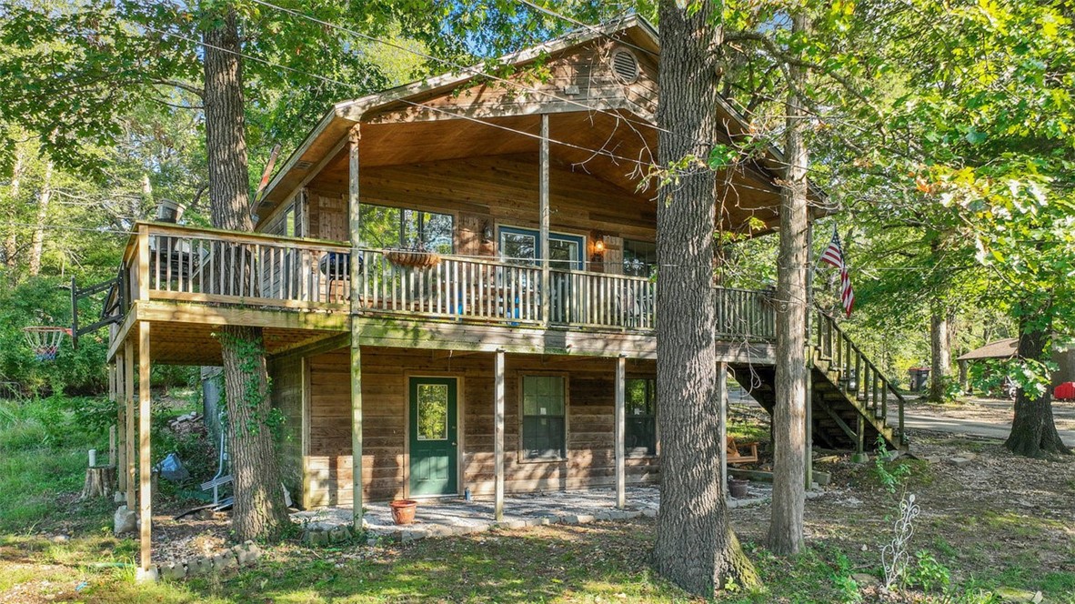 Just 0.4 miles from Beaver Lake in the Beav-o-Rama area, this cedar-sided home offers rustic charm, generous space, and versatility. The main level features two bedrooms along with an open kitchen and living room centered around a fireplace, plus access to a wraparound porch and balcony for relaxing among the trees. A spiral staircase leads to the lower level where you’ll find a second living area along with two unfinished rooms, providing the perfect opportunity to finish them out as bedrooms, offices, or flexible living spaces to fit your needs.
Set on nearly two-thirds of an acre, this home combines character with flexibility and proximity to the lake, making it ideal as a full-time residence, weekend retreat, or investment property.