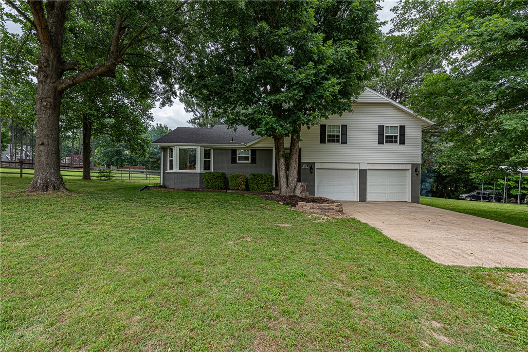 WELCOME HOME! This 4 bedrm 2 bathrm home on 1.51 Acres +/- is the perfect blend of rural and urban living. Only minutes away from Fayetteville eateries, shopping, Blessings Golf Course, & I-49! This split level home boasts an oversized living space w/ wood floors, eat-in dining space, & large kitchen w/ plenty of storage & tasteful updates: granite counters, stainless steel apps, tiled backsplash! Upstairs your primary suite w/ private ensuite feat double sink vanity, private toilet, & shower! Enjoy 3 add'tl bedrms & add'tl full bathrm! Downstairs a mud room connecting to garage & spacious bonus room perfect for an office, media room, & more! Private patio off the bonus to enjoy your property! Main level screened in patio w/ ceiling fan perfect for hosting this summer! Property offers plenty of storage space w/ RV carport, & detached 24x32 2-car garage/shop building! With 1.51 acres +/- this property offers a more private, peaceful feel to set your roots w/ fenced in space, mostly flat lot studded w/ mature trees!