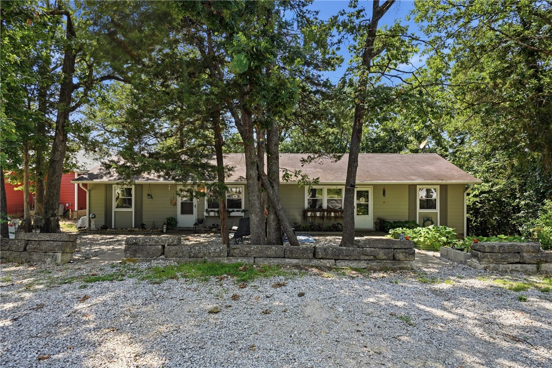 Holiday Island duplex near Table Rock Lake featuring two separate single-level units with flexible living options & rental income potential. The larger 1,032 sq. ft. unit offers 3 bedrooms, 2 bathrooms, & a split-floor plan separating the primary suite from secondary bedrooms for added privacy. The primary suite includes an en suite bath & French doors leading to a private back deck. Recent updates include refrigerator, dishwasher, HVAC, gutters, & water heater. The second 744 sq. ft. unit offers 2 bedrooms, 1 bathroom, an open living & kitchen area, abundant natural light, & new laminate flooring. Both units feature decks, inviting front sitting areas, & a wooded backyard with fire pit, perfect for relaxing or entertaining. A gravel parking area provides ample off-street parking for multiple vehicles. Located near the Holiday Island Marina with access to a community pool, recreation center, tennis courts, walking trails, golf, & outdoor recreation.
