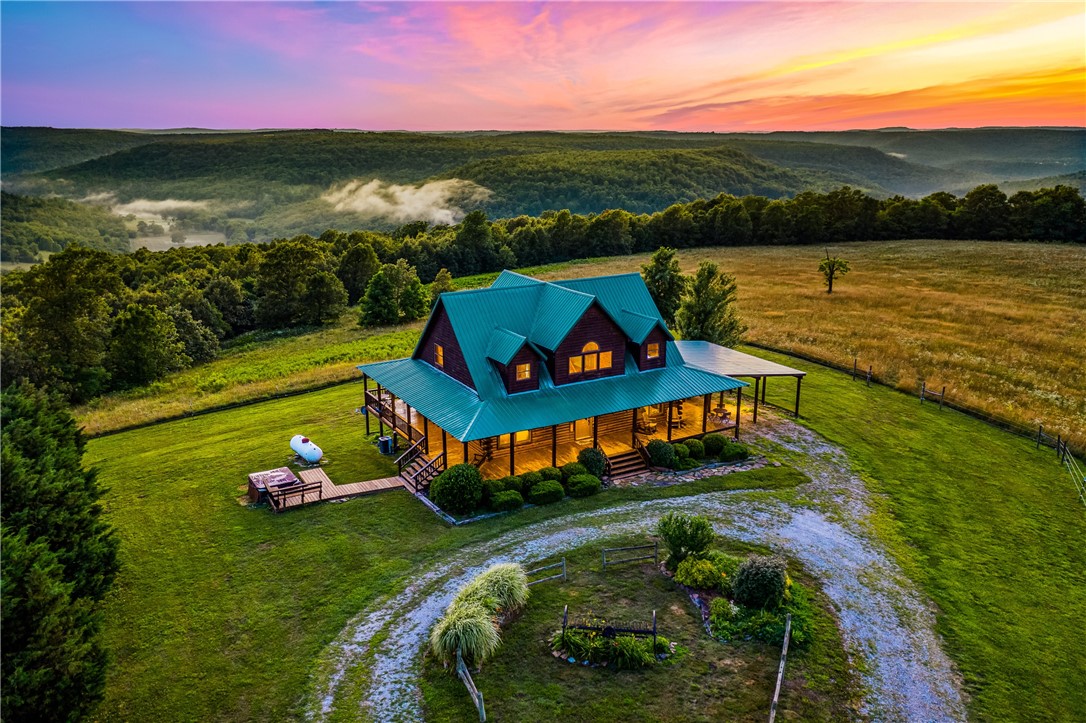 Here's your chance to own this rare Newton County property with 102+/- acres having a nice mix of pasture, hardwoods, a spring and spectacular mountain sunset views from your custom-built Log Cabin, AND one of the renowned "Mountain Springs" natural springs supplies fresh water to the home. This unique property offers 3 bedrooms, an office, 2 baths, an open floor plan highlighted by vaulted ceilings and a stunning catwalk that separates the upstairs bedrooms.  Enjoy year-round outdoor living on the wraparound covered porch, where you can take in spectacular long-distance mountain sunset views or relax in the hot tub under the stars.  Equestrian enthusiasts will appreciate the horse barn and pasture with fabulous trails to ride nearby.  Bring your convertible and ride the scenic mountain highways because the drive is asphalt, leading from a state highway. There's a 24 X 30 carport attached to the home.  Selling furnished and with appliances and hot tub conveying!