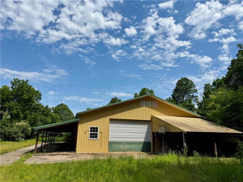 Rare opportunity to own 23 secluded, level & wooded acres with valuable infrastructure already in place, including septic, well, electric, propane, & community boat slip! The value is primarily in the acreage, offering an exceptional setting for a private estate, investment property, short-term rental concept or future build. The existing uninhabitable home features 2 bedrooms, 1 full bath, an eat-in kitchen, dining room, library or office, two covered patios, an attached shop & a metal roof in good condition. The home will require substantial renovation, making it well suited for an experienced investor or buyer seeking a restoration project. Once renovated, it could also serve as temporary living quarters while constructing elsewhere on the property. A boat slip in a co-owned dock w solar power & electricity adds direct access to lake living. With usable terrain, mature woods, privacy, utilities & lake access, this property offers a rare foundation for creating a secluded retreat. See land listing MLS#1354348