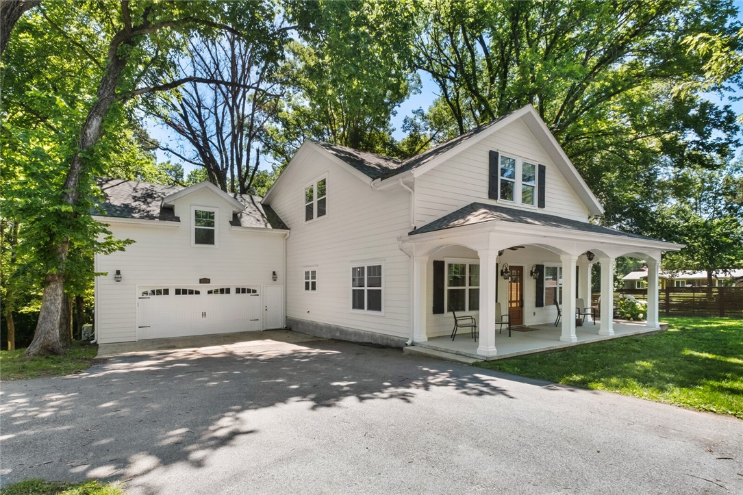Modern farmhouse- space, light, & flexibility-designed for how people live. Thoughtful design, 4–5 bed 3.5 bath nearly 3,000 sq ft of function, comfort & open floorplan of natural light. Transom windows & beautiful beam ceilings add warmth and character. The kitchen features expansive counter space, abundant cabinetry, large island-perfectly positioned to entertain, gather, and cook together -flowing seamlessly into main living and dining. A standout feature is the private lower-level suite, with full bath and direct access to private deck-ideal for guests, home office, or quiet retreat for strong indoor-outdoor connection. Additional primary upstairs adds flexibility for multi-generational living or evolving needs. Upstairs media/bonus room & additional beds and bath, for separation and privacy. Multiple outdoor living spaces, include inviting front porch and side decks surrounded by mature trees—for charm and peace. Quick access to Downtown Rogers, Walmart HQ, and all of NWA, blending convenience and comfort.