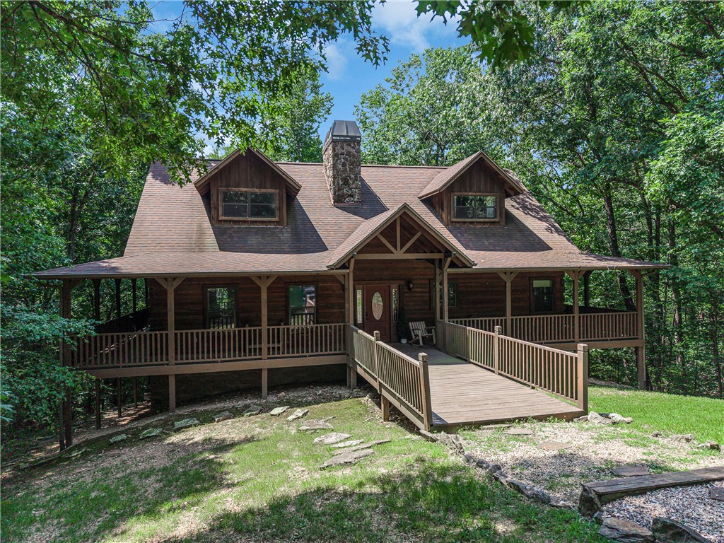 Currently operating as a vacation rental and will come fully furnished. This beautiful Colorado Pine log cabin is located in a private, gated Northwest Arkansas log home community. Featuring a stunning full cedar log interior, this cozy retreat sits beside a peaceful stream and is surrounded by mature trees for exceptional privacy and the relaxing sound of running water. Perfect as a full-time home, vacation retreat, or income-producing rental, the property also includes deeded access to 180 acres of common area for hiking, fishing, wildlife viewing, spring-fed lake, family pavilion, kids zone, biking trails, outdoor recreation, and much more. Experience the beauty of nature and the charm of authentic log cabin living in one of Northwest Arkansas's premier log home communities.