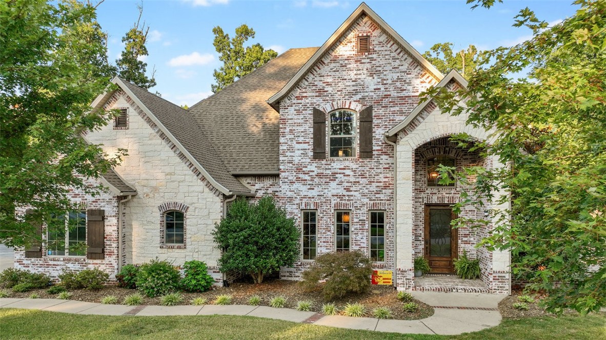 This private, wooded home and acre in the Versailles neighborhood is perfect for gathering loved ones—just minutes from downtown Bentonville and Walmart HQ. Inside, light-filled, open spaces make life easy. The chef’s kitchen, with granite countertops, dual sinks, stainless appliances, and a 36” pro gas range, anchors the home. The main-floor primary suite offers a walk-in shower, jetted tub, dual vanities, and a closet connected to the laundry. Also on the main level: a formal dining room, office, half bath, three-car garage, and inviting living room with beams, brick, and fireplace. Upstairs, three bedrooms with walk-ins, two baths, and a media room with projector and kitchenette await movie nights and sleepovers. Outside, enjoy a covered patio with grill, salt and vinyl liner pool with waterfall, and lush landscaping. An expanded driveway offers plenty of parking for entertaining.