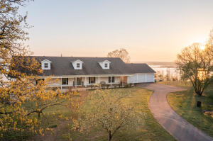 Miraculous, panoramic views and a grand home on the water! On the interior, you will find 3500 sq feet, open floorplan, 3 beds, 2.5 baths, a large office/study with built ins surrounding so it could be used as a library, laundry room and ample storage closets and storage rooms throughout the home. There is also an additional room off of the breezeway that is heated and cooled and could easily be turned into an additional bedroom by adding a closet space. On the exterior you will find a covered porch that wraps around the entire home and 3 car garage with a heated and cooled work room. The large storage space with overhead door access under the home has a cellar with electric and a wood stove that when burning, heats the floors throughout the home. If finished, this could add 1,000 sq f
