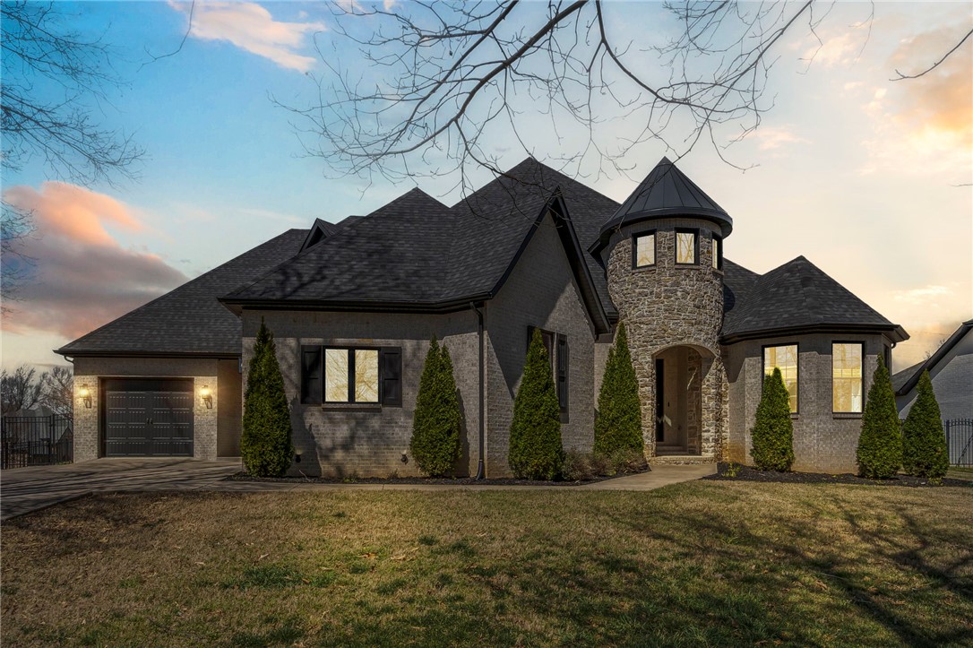 Welcome to Thornbury — one of Springdale's most sought-after communities, offering private trail access to the Razorback Greenway and a full suite of POA amenities. This stunning all-brick, 5-bedroom, 4-bath home sits on an elevated corner lot with soaring 9–10 ft ceilings, 7 ft interior doors, two gas fireplaces, and shiplap accents throughout. The chef's kitchen features GE Profile appliances, double oven, 5-burner gas range, vented hood, farmhouse sink, and a large shelved pantry. The primary suite offers covered patio access, a soaking tub, walk-in shower, and an oversized custom closet with built-in shelving and drawers. Two gas water heaters serve the home efficiently. Storage abounds — from the massive floored walk-in attic and shelved pantry to under-stair storage and closets throughout. A screened porch, hot tub hookup, and gas grill connection make outdoor living effortless. The 3-car garage includes a dedicated dog entry zone. Upstairs bonus room with full bath completes this exceptional home.