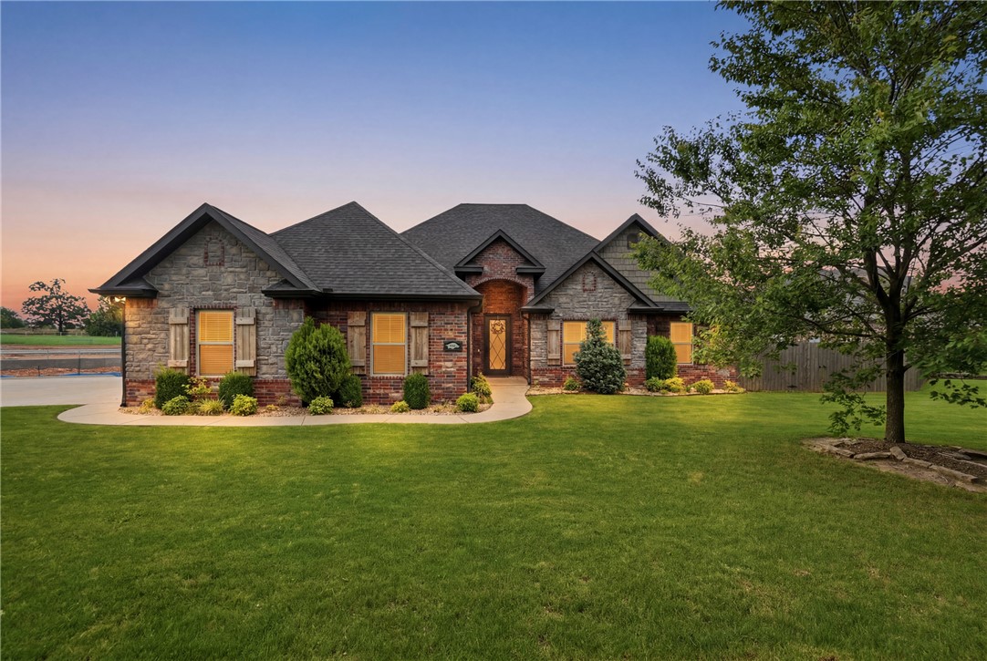 Enjoy comfort and convenience in this beautifully designed Oxford Ridge home on a generous corner lot. The neighborhood pool is directly across the street, with the Bentonville Community Center, shopping, dining, and recreation nearby. The open layout offers four main-level bedrooms, including a flexible office or guest room. The primary suite features a large walk-in shower with a rainfall showerhead, built-in cabinet outlets, and direct access to the walk-through laundry room. The kitchen includes a five-burner gas range, pantry, granite countertops, abundant cabinetry, and ample prep space. Other highlights include recessed lighting, central vacuum, and wired sound in the living and media rooms. Upstairs, the private media room features a 135-inch screen, HD projector, LED lighting, built-in lockers, and a half bath. Outside, the covered patio and spacious backyard are ideal for relaxing or entertaining. The three-car garage includes a Tesla charging station and quick-access storm shelter for added convenience.