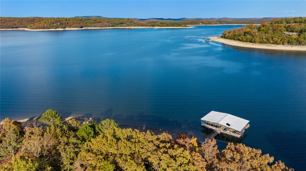 Nestled on 5.79 acres, this enviable lakeside retreat includes a cozy home, a premier 2nd buildable lot, approximately 1,700 ft of Beaver Lake frontage & effortless water access! With 4 bdrms & 3.5 baths spread across 2,968 sf of living space, this home provides ample room for family & guests to relax & unwind. Special features include picture windows framing year-round panoramic lake views, floor-to-ceiling stone wood-burning fireplace, spacious kitchen & open dining area, expansive outdoor deck and seamless lakefront living with water activities just steps from your door.  The property boasts a hard to find co-owned boat dock with 2 boat slips & large swim deck, perfect for your watercrafts & ensuring you're always ready for a day of aquatic adventure or simply soaking in the lake views. Located on a prime lake location & off the shores of Shaddox Cove, this lakeside gem is just a short 10-mile drive to downtown Rogers, offering the perfect balance of serene seclusion & urban convenience. Also for see ML #1295484