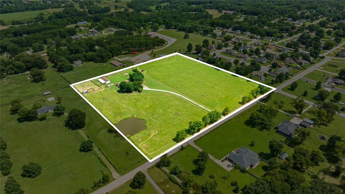 This rare 10 acres is truly a gem...where rural charm & convenience combine.  Adjacent to the city park and Pea Ridge city limits is south boundary.  Bring the horses or know there is room to grow.  Great potential to own a little piece of country close to everything in the booming town of Pea Ridge! The property includes a pond, fenced, flat pasture, outbuildings for all the toys & critters, and mature trees. Home is livable or awaiting your dreams:  full brick exterior, 2 car attached garage, wood fireplace with brick surround in living room, eat-in kitchen, 3 bedrooms, 2 baths, laundry area off of garage entrance with sink & countertop and upper and lower cabinets for storage. Kitchen boasts lots of solid wood cabinets for plenty of storage space. Main bedroom features an en-suite 3/4 bathroom with tile walk-in shower. Back porch is now a sunroom for extra living space (no HVAC currently). Close to Pea Ridge Schools, local amenities, & easy access to all NWA attractions!
