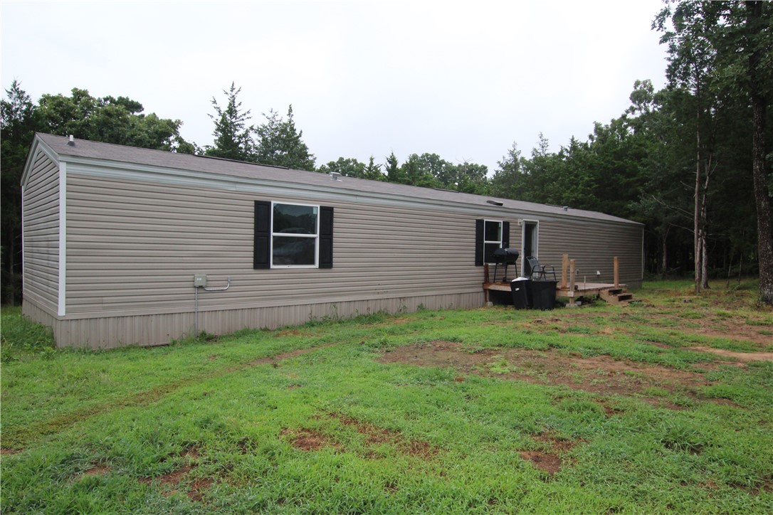 Looking for a peace of personal paradise? This rural home has 3 bedrooms and 2 full baths, one with a custom walk-in shower. Kitchen with a bar to serve quick meals, handy laundry in the hallway to the master bedroom. Only 3 years old, and in great shape. All appliances convey that match the decor. Another large building is on the property with wood siding and metal roof. Its a mother-in-laws quarter that is being constructed inside.It is 50x16. Electricity already established there with its own service, if you want to make it a rental or a shop. Lots of land available to build another property, live in the mobile while you are building your home, then rent it out for extra income.  Lots of deer plots, and other wildlife that frequent the property. Fenced back yard for your pets or kids. Neighbors are all friendly and fresh eggs across the street. Come take a look at it.