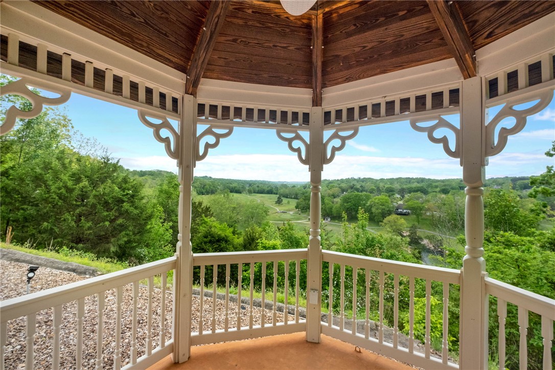 This 4-bedroom, 3-bath home on 1.65 acres perched above the 9th & 18th holes of Scotsdale Golf Course offers spectacular views! The living room flows into a sunroom with floor-to-ceiling windows framing panoramic views of the fairway valley, rolling Ozark hills & unforgettable sunsets-plus a front-row seat to 4th of July fireworks. The main living area also includes cathedral ceilings, fireplace, wet bar, hardwood floors & a deck-perfect for entertaining. The eat-in kitchen features granite counters, a large island & a pantry. The primary suite includes a generous walk-in closet that connects to the laundry room. Two guest bedrooms complete the main floor. The walk-out basement adds a second living area, bedroom, office, storage & workshop with golf-cart-width double doors. The oversized 3-car garage includes extra storage & a workbench. New roof (2025), new water heater (2026). Enjoy the outdoors in the charming hilltop gazebo with fabulous views. Minutes to Loch Lomond and the Little Sugar mountain biking trails.