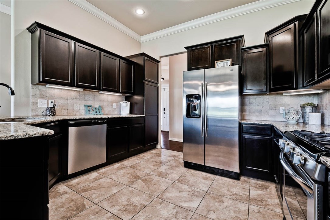 This kitchen, y'all, is worth the look with a great layout, cabinets, counter space, and stainless steel appliances (built in microwave new in 2019).   Home is in great condition and features 3 bedrooms, 2 bathrooms, 2 car garage, with a split floor plan.   Open floor plan features kitchen, bar, dining and living space. There are Scraped wood floors throughout living areas.  Cuddle up to the fireplace in the living room for those movie nights.    Sit out on the covered back patio for you morning coffee with view of field and trees and wild life!  Life doesn't get much better than this!
