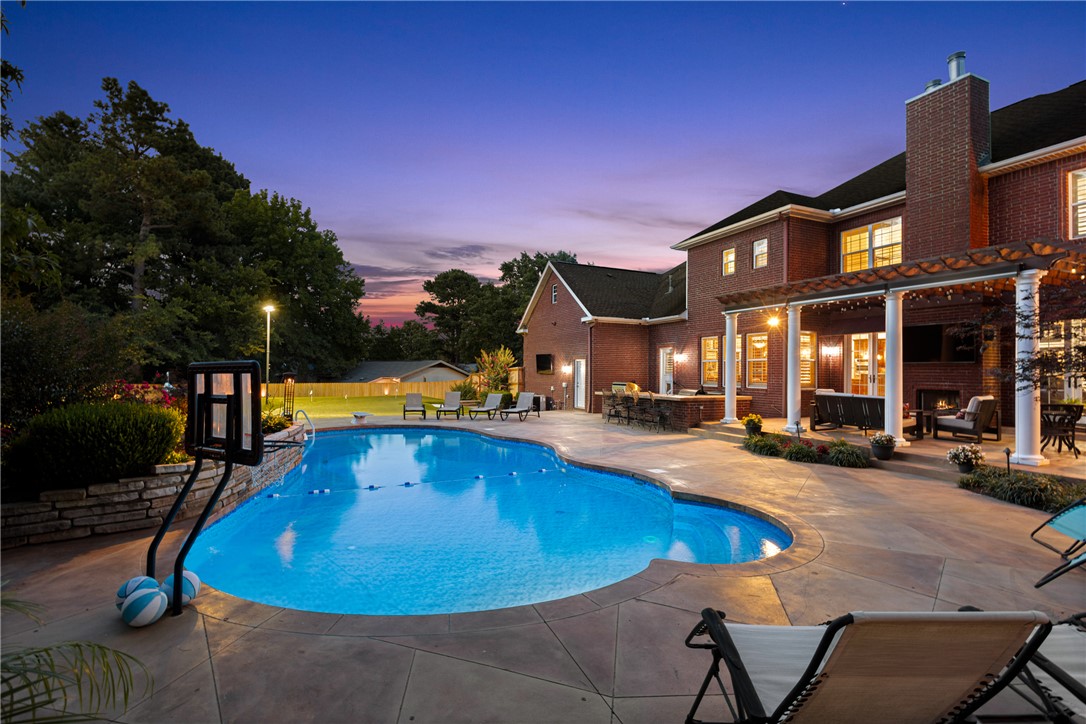Exceptional custom estate steps from Fayetteville Country Club, timeless design & resort-style outdoor retreat. Landscaped with classic brick architecture, Brazilian Cherry hardwood floors, plantation shutters & new interior paint. Thoughtfully designed floor plan features formal dining, an executive office, flex/exercise room, guest suite, spacious mudroom w/pool bath, oversized laundry & 4-car garage. Kitchen has granite counters, large pantry, 6-burner gas range & built-in stainless appliances. Upstairs, luxurious primary suite features a private balcony, spa-inspired bath & oversized walk-in closet w/cedar closet. Secondary suite, 4th guest bed & guest bath. Large Bonus with wet bar. Outdoor living with a covered patio, fireplace, automated shades, outdoor kitchen and saltwater pool with slide, diving board and basketball goal. Hot tub from Burton. Custom 2700 SF lighted Celebrity Green practice facility with putting, chipping and sand traps. New 2026 roof, 26 solar panels, Generac generator, 2025 fence & more!