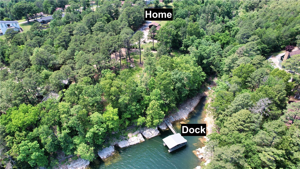 Experience the ultimate lake lifestyle in this cozy, rustic 2,450 sqft cabin on the north end of Beaver Lake. Situated on 1.68 acres across two parcels, this property features a gentle 6-ft easement leading to your private single-slip boat dock with a lift in a quiet cove. The home boasts a 2024 roof and freshly stained cedar exterior. The interior shines with refinished oak hardwood floors, tongue-and-groove ceilings, and cedar-trimmed windows. The main level offers a kitchen with custom oak cabinets and Corian counters, a dining area with cathedral ceilings and a wood stove, and a bright living room with walls of windows overlooking the lake. The layout includes a main-level bedroom and full bathroom. A spacious loft with skylights and a half bath can be found on 2nd level. While a walk-out basement features a third bedroom and a full bath with a cast iron clawfoot tub and a cedar-lined walk-in closet. Complete with a detached 2-car garage and wrap-around porch, this private retreat is lake living at its finest.