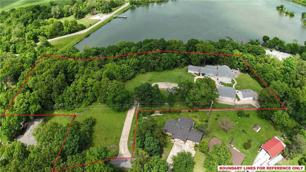 Stunning lakefront estate offering exceptional privacy, luxury, & breathtaking views. This expansive 6,057 sq ft home features 3 beds & 3 baths, including 2 primary suites with private living areas. Two additional spacious living areas, a formal dining room, secure safe room, abundant storage, & direct patio access from every room create seamless indoor-outdoor living. A guest house located at the rear of the 3-car garage offers 510 sq ft with a studio apartment/mother-in-law suite, complete with an indoor pistol range/walk-in closet. Additional 2-car garage plus ample guest & RV parking provide exceptional flexibility. The expansive deck and stone patio feature a step-down fire pit & decorative waterfall feature (currently not operational but able to be restored). Thoughtfully designed with well-separated living spaces, this unique property offers endless possibilities as a private luxury residence, multi-generational retreat, executive getaway, conference-style setting, or potential income-producing opportunity.