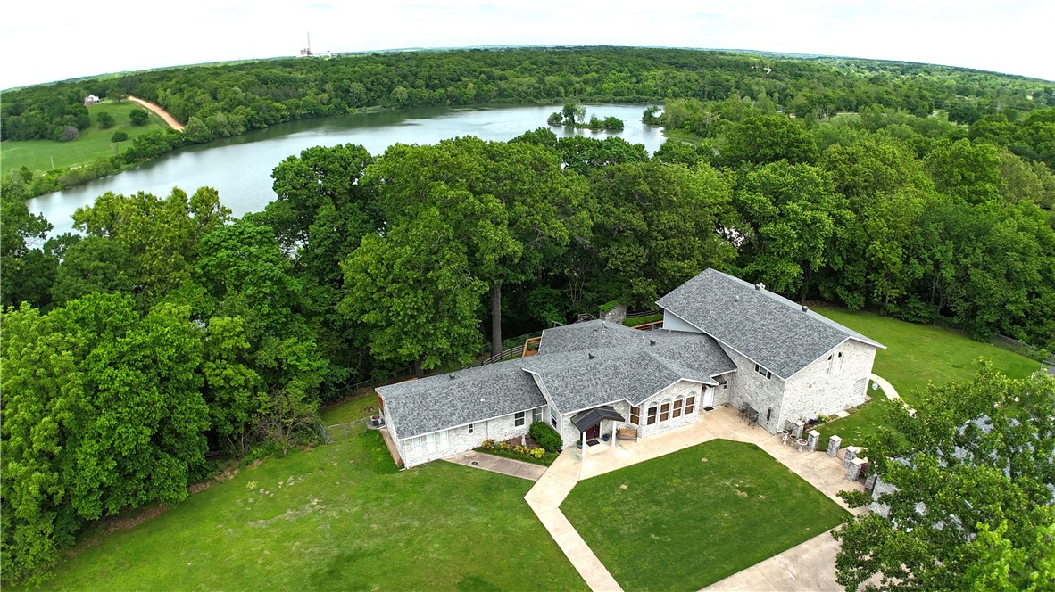 Stunning estate home offering exceptional privacy & beautiful lake views. This expansive 6,057 sq ft home features 3 beds & 3 baths, including 2 primary suites with their own living areas. 2 additional spacious living areas, a formal dining room, a secure safe room, abundant storage, & direct patio access from every room—creating seamless indoor-outdoor living. A guest house in the rear of the 3-car garage has 510 sq ft. This studio apartment/mother-in-law suite comes complete with an indoor pistol range/walk-in closet. Additional 2-car garage and additional parking, both for guests & RVs. Expansive deck and stone patio area featuring a step-down fire pit & a decorative waterfall feature (currently not in operation but able to be restored). Thoughtfully designed with well-separated living spaces, this property offers flexibility as a private luxury residence, multi-generational living, executive retreat, conference-style setting, or potential income-producing opportunity.