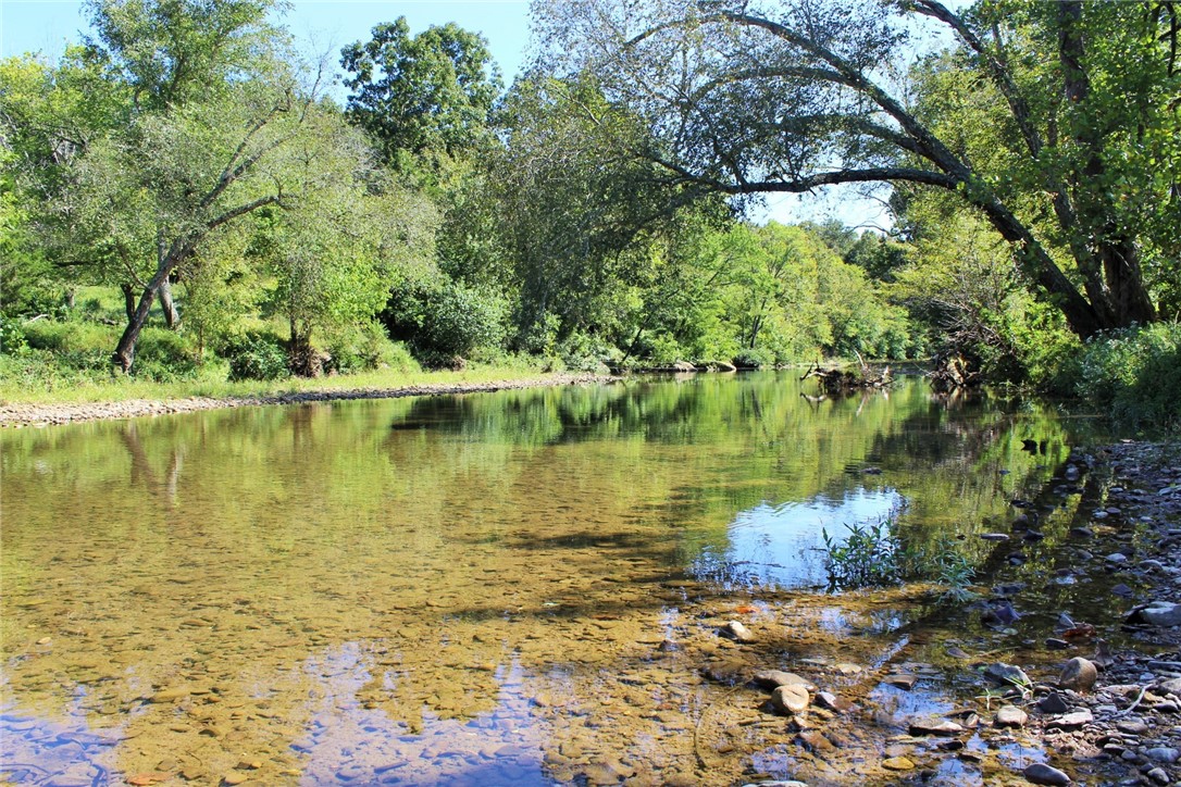 Located just 16 miles southeast of Huntsville, this 270-acre tract offers a rare combination of river frontage, open pasture, and recreational opportunity. Accessed via County Road 2545 and only 300 yards off Hwy 74, the property features approximately 3/4 mile of Kings River frontage—ideal for fishing, kayaking, and waterfowl hunting. Currently used for cattle, the land also provides excellent wildlife habitat with frequent sightings of deer, turkey, and small game. Electric and rural water are already on-site, making it a great candidate for a homesite or cabin retreat. The north boundary includes a scenic bluff line offering panoramic views of the river and surrounding countryside. A conservation easement is in place to protect the natural beauty of the land. Whether you're looking for a working farm, recreational haven, or private getaway, this property is a standout in the Ozarks.