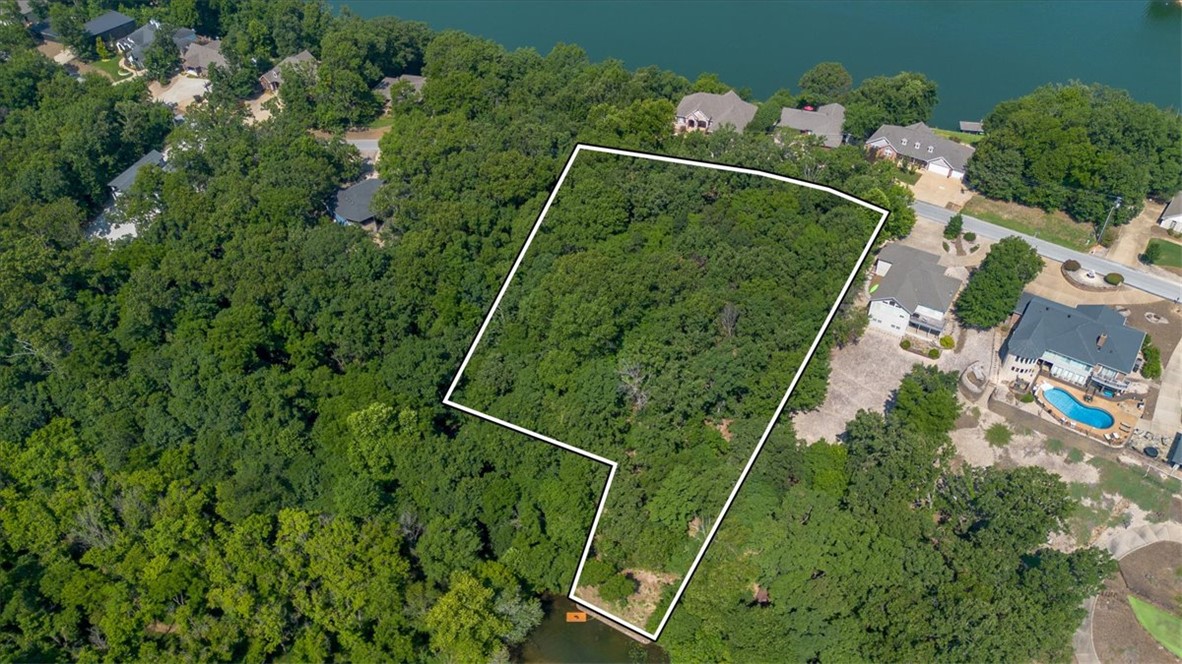 Build your dream waterfront sanctuary on Loch Lomond! This premier 1.45-acre double lot, that has perc tested for a 3 bedroom home on each lot, on Stonehaven Drive features direct lake access complete with a private floating dock and custom chill-out pad ready for relaxing or entertaining. Featuring a walking path to the water, mature trees, stunning lake views, a seawall, and a sloped terrain ideal for a walk-out basement design. It's even ready for you to put in your own permanent dock. Enjoy peaceful cove living on Bella Vista's largest lake with easy access to golf, trails, and dining.
