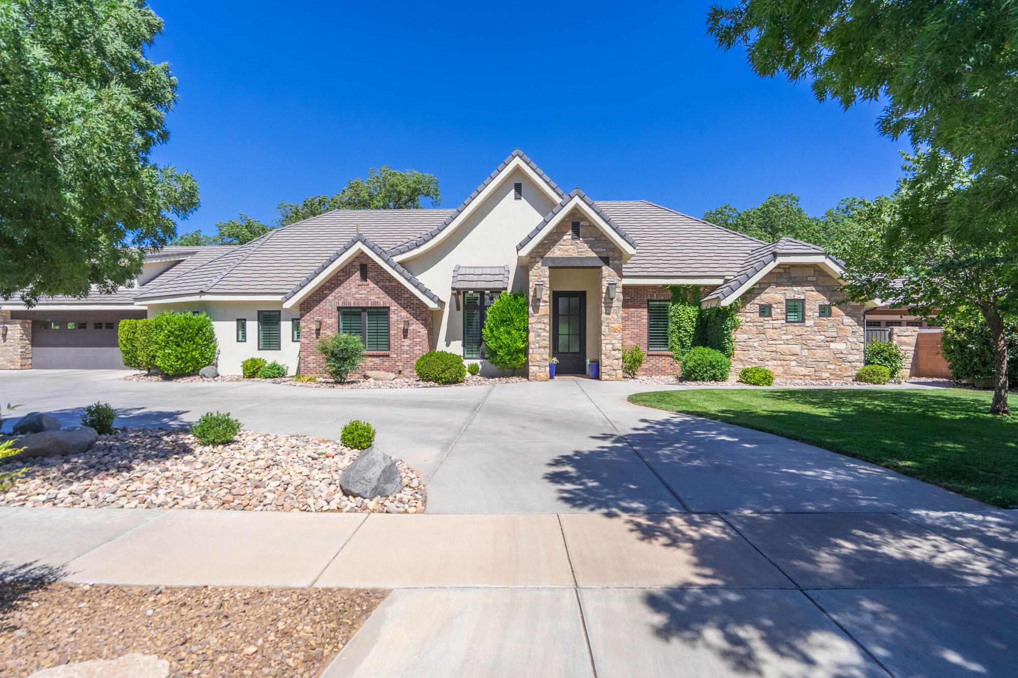 Situated on a beautifully landscaped .74-acre lot, this exceptional property offers a rare combination of luxury, privacy, and versatility. Thoughtfully designed to balance gathering spaces with private retreats, the home features a welcoming entryway separated from the main living areas, while the bedrooms are strategically positioned away from entertainment spaces for added comfort and tranquility.

Designed with ADA-compliant features, the home offers wider hallways, larger doorways, and an open-concept layout that enhances both accessibility and everyday living. Tile and engineered hardwood flooring extend throughout the main level, creating a seamless blend of elegance and durability.

One of the home's most remarkable features is the backyard retreat. Mature trees create a rare outdoor sanctuary, providing cooling shade, privacy, and year-round enjoyment. Whether relaxing with family, entertaining guests, or enjoying Southern Utah's beautiful evenings, this outdoor space offers a setting that is both peaceful and inviting.

Above the oversized garage is a fully finished accessory dwelling unit (ADU) currently operating as a successful Airbnb. Ideal for supplemental income, multigenerational living, or private guest accommodations, this flexible space adds tremendous value. Airbnb income history and financial information are available upon request.

The home also includes a spacious bonus room above the main garage, perfect for a media room, home office, gym, playroom, or additional guest space. Plumbing is already in place for the future addition of a half bath, offering even greater flexibility.

Combining thoughtful design, premium finishes, accessibility features, an income-producing ADU, and an exceptional backyard setting, this property presents a rare opportunity to enjoy luxury living on nearly three-quarters of an acre.