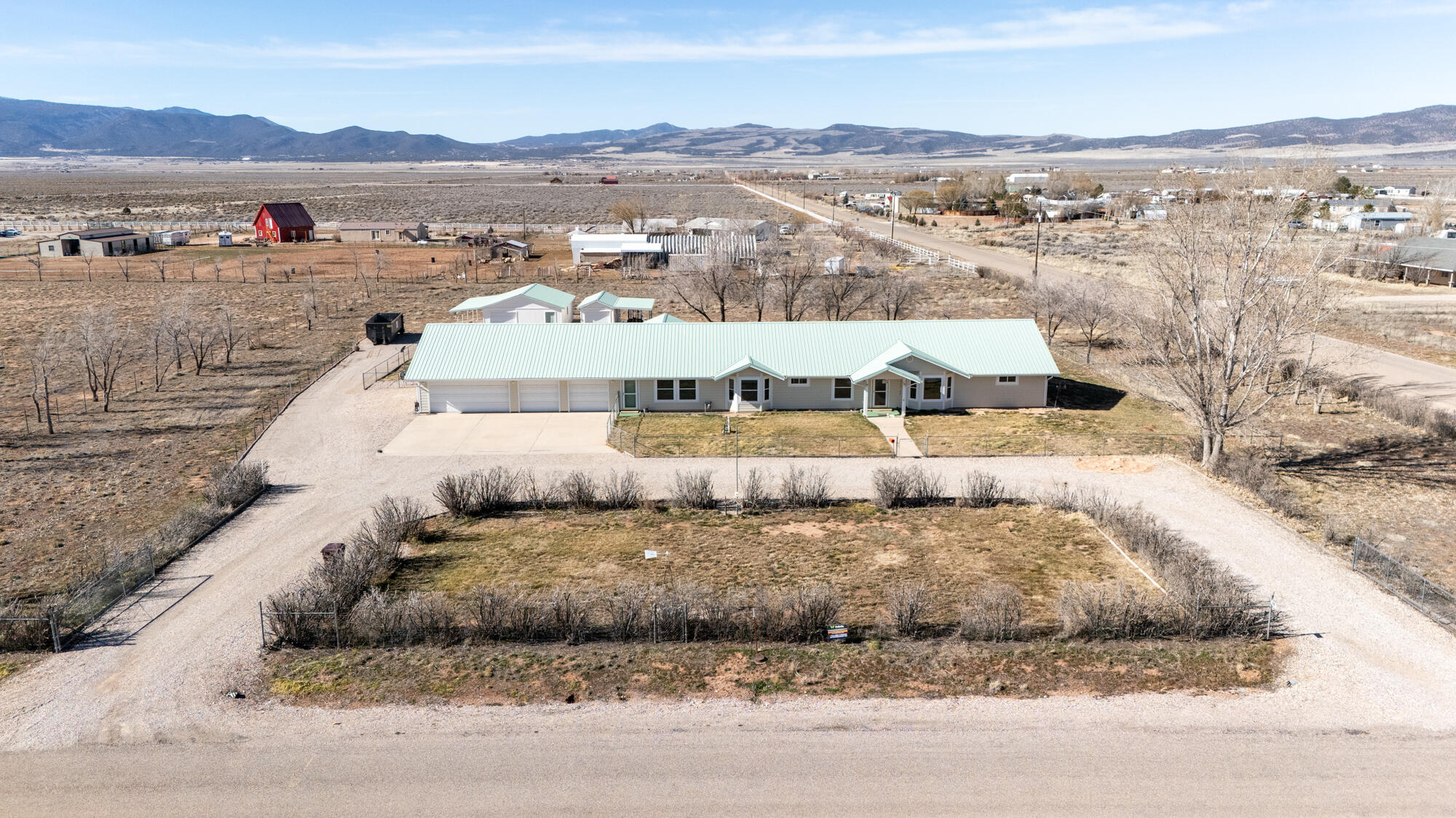 Spacious single-level 3,280 sq ft home with 3 bedrooms and 2 bathrooms on 2.5 acres in Meadows Ranch East. The home offers two separate family rooms, providing flexible living space for entertaining, a media room, or everyday use. The large kitchen includes ample cabinetry and storage. A spacious laundry room features extensive cabinets, countertop space, and a utility sink. The primary suite includes a jetted tub and separate shower. The oversized 4-car garage offers extra space, built-in cabinets, a sink, and a heater, making it functional year-round. The yard is fully fenced and includes two workshops/sheds in the backyard, each with a garage door and suitable for a workshop or additional storage for ATVs, toys, or equipment. Recent updates include luxury vinyl plank flooring, interior paint, new windows, James Hardie board siding, a garage heater, and rain gutters. An enclosed sunroom provides additional usable space for an office, TV room, or relaxation area. Property comes with 3/4 AFCT of water with the Meadows Ranch Community Well and is $40 a month. Located on a corner lot with mountain and valley views in all directions and sunsets to the west. The landscaped portion of the yard is fully fenced, with the back portion of the lot left open for yard expansion or animals.