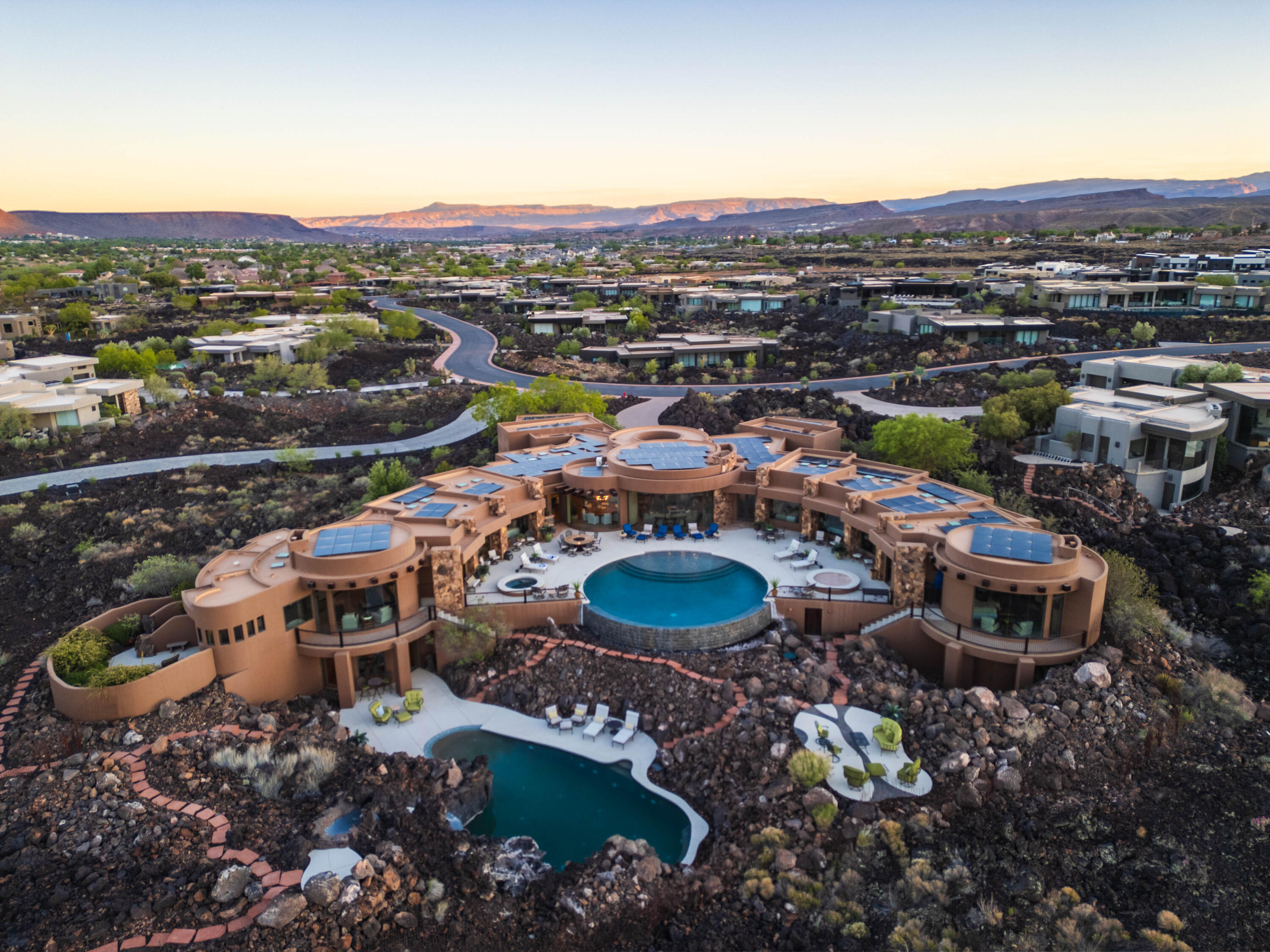 Is there a 7-bedroom luxury estate the famous Entrada at Snow Canyon golf course in St. George designed for unforgettable gatherings and lifelong memories? YES, this exquisite estate sits on 2.70 acres that blends resort-style living, 7 private ensuite retreats, and breathtaking red rock views into a setting where every space invites connection, celebration, and quiet escape.

Welcome to The Squash Blossom Estate, a home where architecture becomes the backdrop for a lifetime of moments shared with family and friends. Inspired by the sacred symbolism of the Navajo Squash Blossom and the open-air elegance of Mexican villas, the design centers around togetherness, with two stunning pools at its heart and every room flowing effortlessly toward it.

Mornings begin with sunlight spilling across private patios as each bedroom opens directly to the central pool, making it easy for guests and family to gather, laugh, and start the day together. Afternoons drift between shaded lounge spaces and quiet corners, while the hidden grotto pool offers a sense of discovery, complete with a tucked-away underwater sitting area that feels like a secret meant to be shared.

As evening falls, the home transforms. Fires glow across six outdoor patios, conversations stretch long into the night, and meals are shared around a custom fire pit table under the desert sky. Inside and out, every space is designed to bring people closer, whether it is a lively celebration or a quiet moment of reflection.

The primary suite offers its own private retreat, including a secluded outdoor shower and lounge space, creating a sense of escape even within the home. Throughout, artisan craftsmanship tells a deeper story, from hand-laid tile mosaics to symbolic metalwork, adding layers of meaning and intention to every detail.

This is more than a home. It is a place where traditions begin, memories deepen, and every visit feels like coming back to something truly special. Buyer to verify all info.