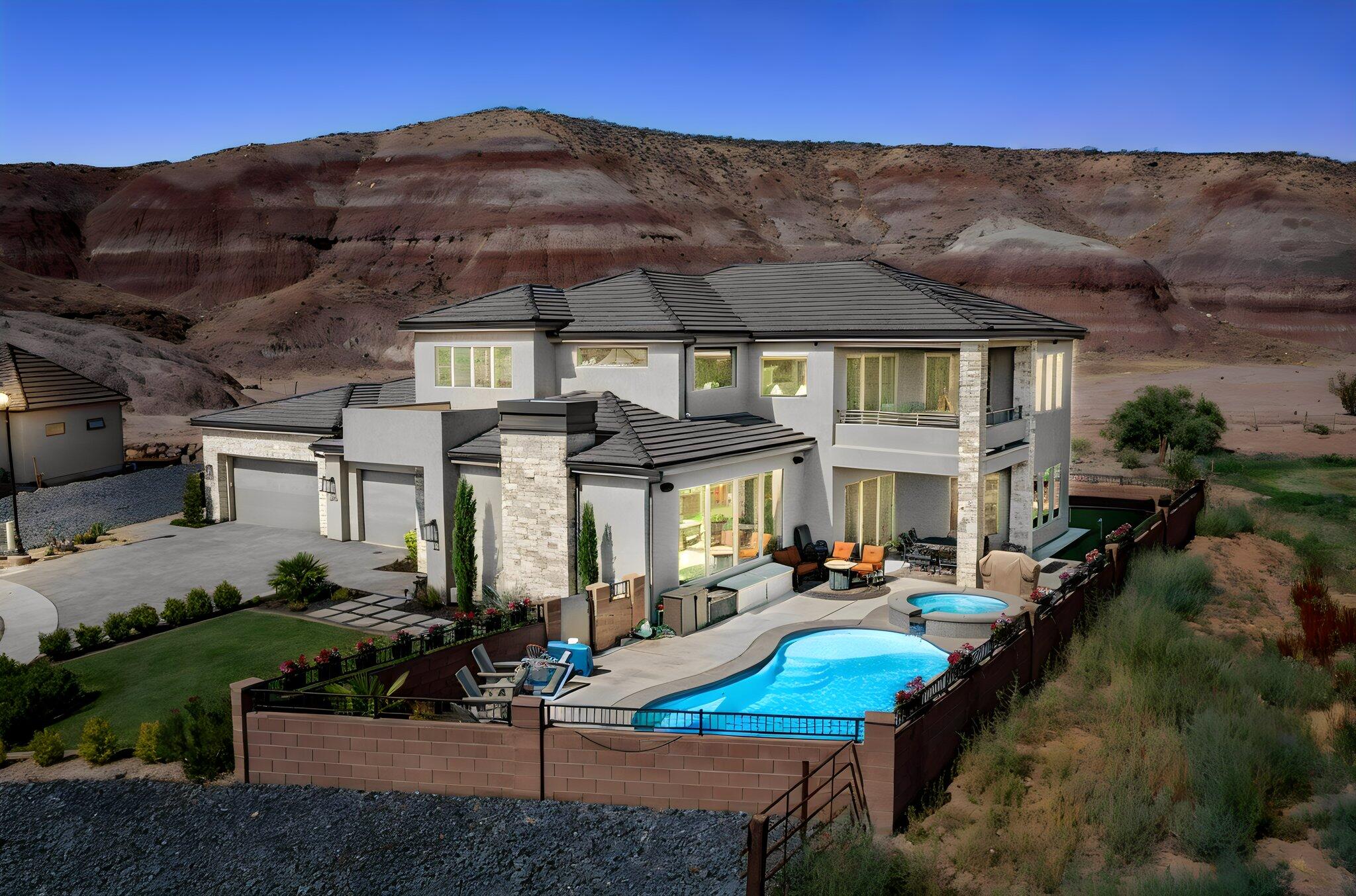 Introducing the first resale opportunity in River Bend, Sunbrook's newest enclave of luxury custom homes. Completed in 2024, River Bend is an exclusive cul-de-sac of just fifteen custom residences within the prestigious 27-hole Sunbrook Golf Community. Thoughtfully designed by its original owners, this exceptional home offers a rare combination of privacy, breathtaking scenery, and resort-style living. Situated at the end of Lost Creek Circle, the property is surrounded by nature on nearly every side. To the west, over 6,300 acres of Bureau of Land Management land provide an untouched desert backdrop. The Santa Clara River meanders nearby, while open farmland borders the north. With no home directly across the street and generous separation from neighboring properties, the setting offers remarkable privacy and unobstructed panoramic views stretching from Pine Valley Mountain to the dramatic red cliffs of Snow Canyon State Park. Designed with both grand entertaining and comfortable everyday living in mind, the home features 5 spacious bedrooms, including 3 luxurious en-suite suites, 5 bathrooms, a dramatic 22-foot entry, a spectacular 12-foot great room overlooking the pool and spa, and 10-foot ceilings throughout the remainder of the home. The expansive open-concept floor plan seamlessly connects the great room, gourmet kitchen, and dining area, creating an ideal gathering space for family and guests. The oversized garage provides abundant room for vehicles and storage, while a hidden walk-in pantry offers both convenience and style. A dedicated sewing room can easily serve as a sixth bedroom, hobby room, or private studio, and the extraordinary primary suite features a walk-in closet large enough to rival a bedroom. Upstairs, a private office and a second family room capture some of the home's most spectacular views. For golf enthusiasts, the property offers an amenity rarely found in residential real estate--a professional-grade Full Swing golf simulator, endorsed by Tiger Woods, featuring a 14-foot impact screen that allows you to play many of the world's most celebrated golf courses from the comfort of home. The simulator also accommodates numerous other sports and can easily double as an impressive home theater.
The outdoor living spaces are equally exceptional. A sparkling pool and spa are complemented by an approximately 500-square-foot artificial turf putting green with five holes, creating a true private resort where recreation, relaxation, and entertaining come together effortlessly. This is more than a home--it's a once-in-a-generation opportunity to own one of the finest residences in Sunbrook's newest luxury neighborhood, where extraordinary privacy, world-class amenities, and unforgettable views define everyday living.