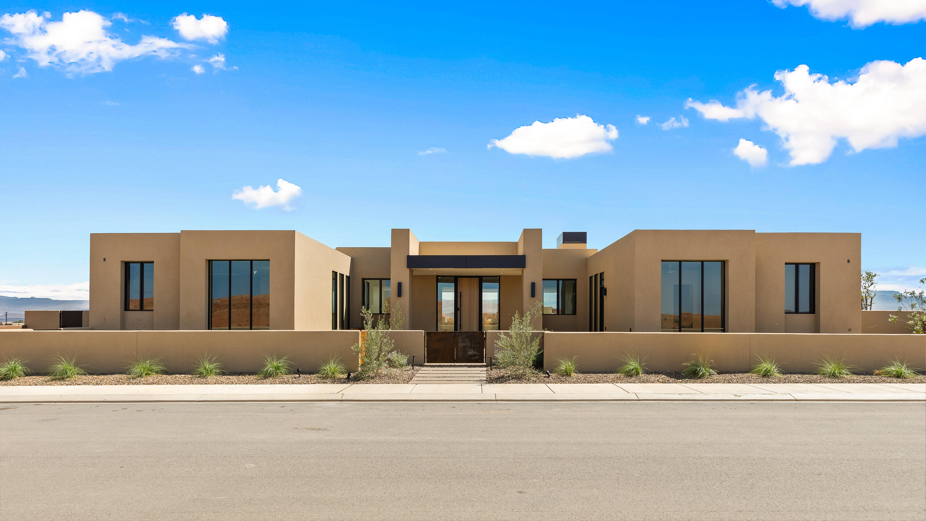 Brand new modern desert masterpiece offering 3,950 square feet of luxurious living space. This thoughtfully designed home features 4 bedrooms, all with their own private ensuite bathrooms and exterior entrances, plus an additional half bath.
The expansive open concept layout is enhanced by oversized glass sliders that create a seamless connection between the interior and outdoor living spaces. The chef's kitchen features professional Signature appliances, an impressive 11 foot island, leathered Taj Mahal countertops, and a full butler's pantry with extensive storage, a wine refrigerator, and an ice maker. A flexible bonus room with a beverage refrigerator and microwave provides the perfect space for entertaining or accommodating guests.
The primary suite features spa like upgrades, including two separate toilet rooms, a freestanding soaking tub, an oversized glass shower, a makeup vanity, and a custom walk in closet with washer and dryer hookups.
Nearly 1,000 square feet of covered rear patio space invites year round outdoor living. The east facing backyard features a pool and spa with an automatic cover, a fire pit, and a private miniature golf area. Additional features include a 38 foot boat garage, an oversized two car garage with epoxy flooring, a three sided custom fireplace with a textured plaster surround, and designer tile and lighting throughout. Energy efficient features include tankless water heaters, blown in insulation, and Low E glass windows. The home is also prewired for security, audio, automatic shades, and additional smart home technology. A gated courtyard with a custom water feature creates a striking and memorable welcome, while natural textures and clean architectural lines bring the home's Amangiri inspired design to life.
The HOA includes full yard maintenance and access to three pools, two hot tubs, a fitness center, and two pickleball courts. Residents enjoy live music, community events, and annual celebrations, including the Car Show, Sky Fest Hot Air Balloon Festival, and Pioneer Day Celebration. Additional benefits include discounts and VIP access to golf, events, and UTV and watercraft rentals.
Located just minutes from Sand Hollow Reservoir and championship golf, this exceptional home offers an unmatched combination of luxury, privacy, and the Southern Utah lifestyle.