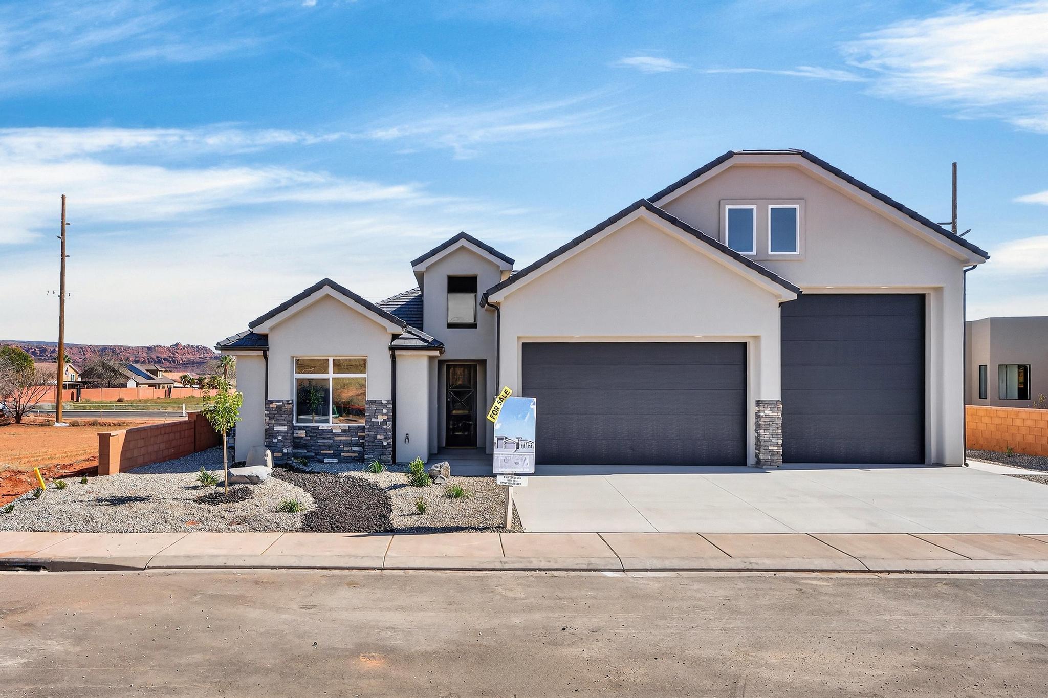 Welcome to Black Stone in beautiful Ivins, breathtaking Red Mountain backdrop. This brand-new home showcases stunning views, thoughtful design, and elevated finishes throughout. An inviting open floor plan is highlighted by luxury wood-plank flooring, both stylish and durable, perfectly suited for Southern Utah living. The kitchen is truly the heart of the home, featuring custom knotty alder cabinetry with rich natural wood grain, soft-close hardware, and detailed craftsmanship. Designer selected granite countertops pair seamlessly with a modern stacked tile backsplash and stainless-steel appliances, creating a warm space ideal for everyday living and entertaining. The spacious living room offers tall ceilings and is plumbed for a future fireplace, providing the perfect setting to gather and relax. A convenient half bath is located just off the main living area for guests. The main level includes two secondary bedrooms with a full bathroom, along with a beautifully appointed primary suite. The primary bath features sleek finishes and a spa-like atmosphere, complete with a 3/8" Euro glass shower enclosure. Upstairs, you'll find a versatile bonus room with its own full bathroom, ideal for a media room, office, gym, or private guest retreat. It is also plumbed for a mini-split system, allowing for customized climate control. Additional highlights include the entire home plumbed for central vacuum, a fully landscaped yard with room for a future pool, and exceptional garage space with a 12' wide x 14' tall RV garage door plus an oversized two-car garage with an 18' wide, 10' tall door. Offering space, quality craftsmanship, and unforgettable Red Mountain views, this home is a rare opportunity in one of Ivins' most desirable communities.