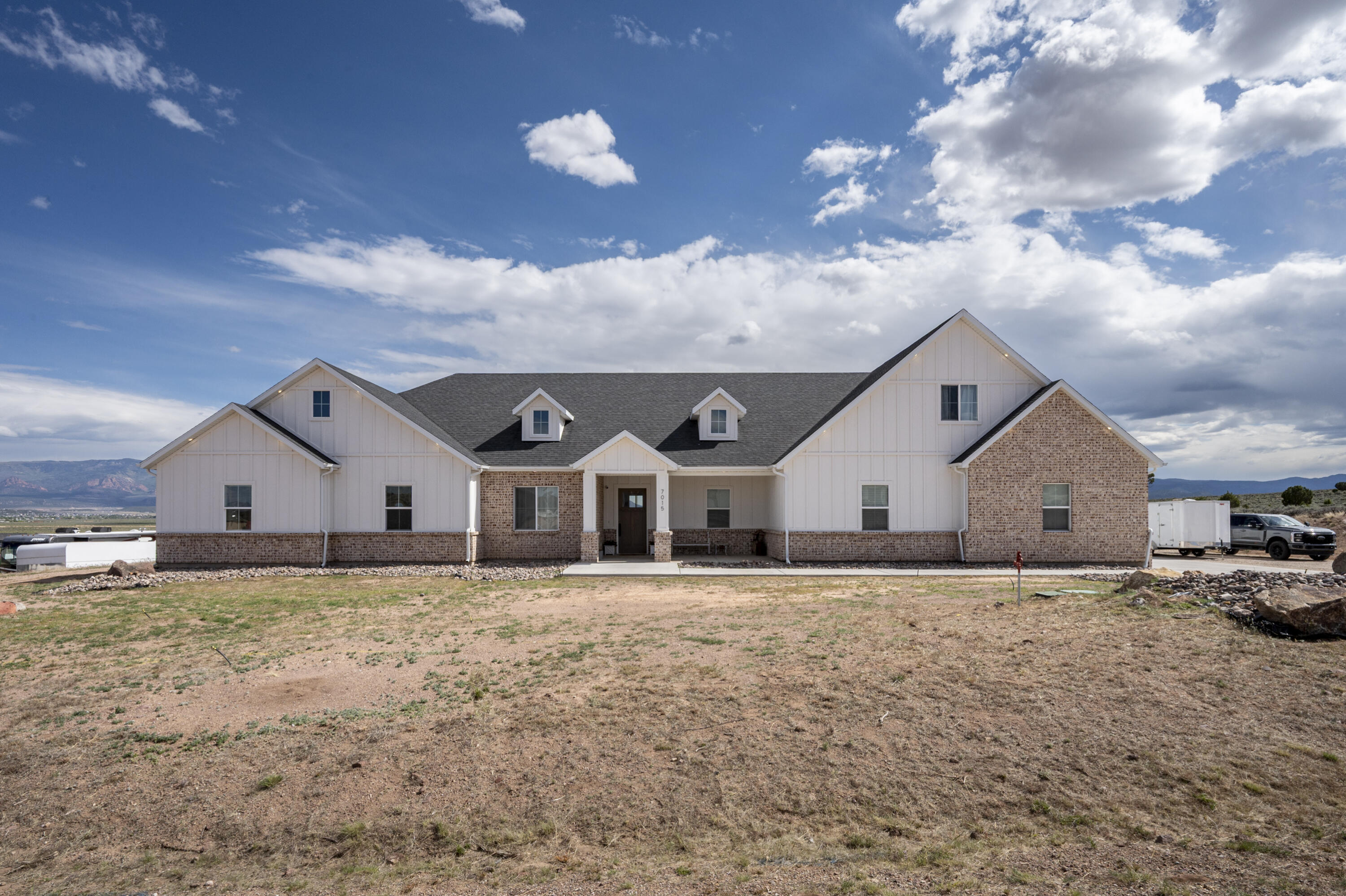 Beautiful custom home located on 1.10 acres in the desirable Bridle Path West subdivision offering 3,994 sq ft, 5 bedrooms, and 3.5 bathrooms with incredible views, thoughtful upgrades, and room to spread out. From the moment you walk in, the open great room showcases stunning beamed ceilings, a beautiful fireplace, and large windows that bring in natural light and surrounding views. The spacious layout flows perfectly into the kitchen and dining areas, creating an ideal setup for entertaining and everyday living. The kitchen features two dishwashers, abundant cabinet space, and a large walk-in butler's pantry for additional storage and prep space. The formal dining room is separated by beautiful sliding barn doors and could easily function as an office, sitting room, or flex space. Upstairs offers an additional entertainment or hangout area perfect for a game room, media space, or additional family room setup. The spacious primary suite includes dual vanities, a soaking tub, walk-in shower, and convenient washer and dryer hookups located directly within the primary bathroom. The large laundry room offers extra cabinetry, counter space, and additional storage throughout. Outside, enjoy the oversized covered back patio complete with spa and grill hookups, making it the perfect place to relax and take in the mountain and valley views. The property also features raised garden beds, fenced areas, RV power hookup, and plenty of room for animals, toys, trailers, or future improvements. The heated oversized garage includes 220V power, a sink, urinal, and excellent storage space. The barn/shop has power and offers incredible versatility for livestock, hobbies, workshop space, equipment storage, or recreational toys. Located in a great area with wide open views while still being close to town and amenities, this property offers the perfect blend of comfort, functionality, and country living. Some furnishings, one chicken coop, and other various items are negotiable upon acceptable offer. Not included: the shed and the smaller chicken coop.