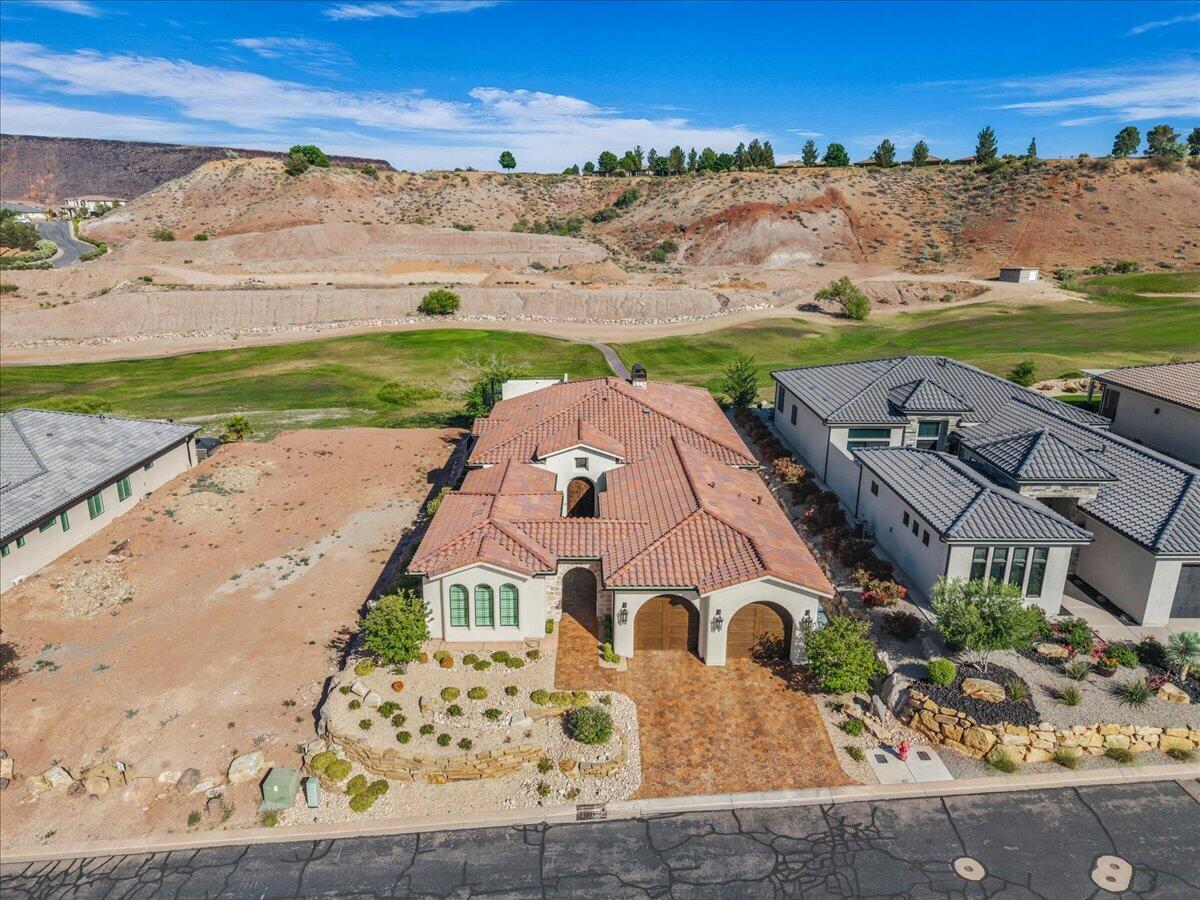 Located on the prestigious Sunbrook Golf Course, this stunning residence blends timeless Mediterranean Revival architecture with sophisticated modern design. Perfectly positioned with an east-facing orientation, the home captures breathtaking views of the golf course, surrounding valley, and mountains from both the main living spaces and the incredible rooftop deck, the perfect setting to enjoy Southern Utah sunsets. Inside, soaring ceilings, thoughtfully curated lighting, and exceptional craftsmanship create an atmosphere of warmth and elegance. Built with quality in mind, the home features 2x6 construction, beautiful Arto pavers and tile throughout, an oversized two-car garage with dramatic Vidor doors, dual EV charging outlets, and five separate HVAC zones for personalized comfort. The gourmet kitchen is designed to impress, showcasing Wolf and Sub-Zero appliances, including a steam oven, quartzite countertops, rich walnut cabinetry, and a spacious pantry. With four bedrooms, 4.5 baths, an infrared sauna, and carefully selected finishes throughout, this home offers a seamless blend of luxury, comfort, and effortless golf course living.