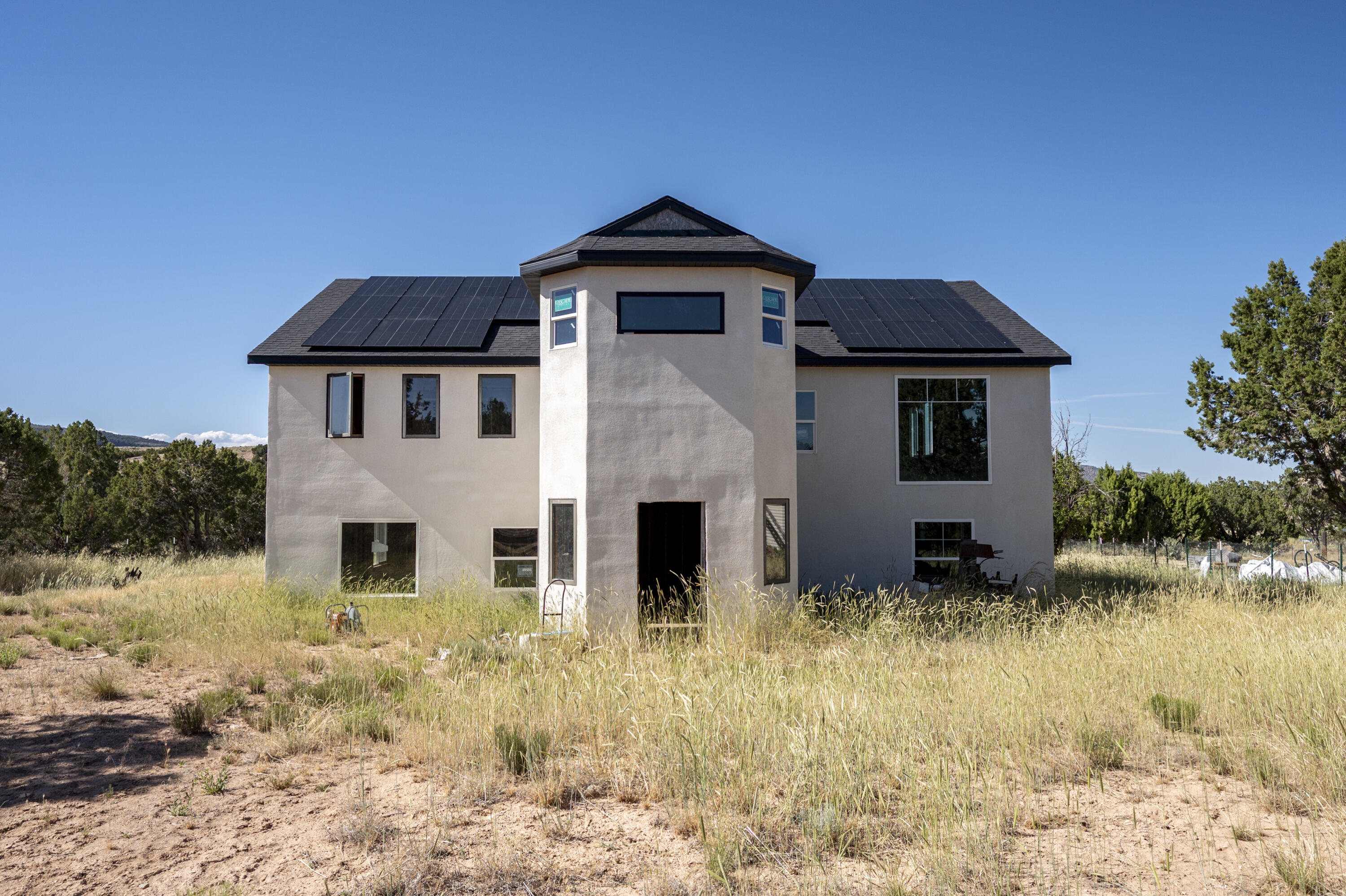 What a great opportunity to own land in a quiet neighborhood and finish building your dream home. The house was started in 2005. A new roof was installed in 2021 along with stucco, windows, framing and fencing. There are 24 solar panels and 2 Tesla batteries for a complete off-grid electrical system. It is framed to have a primary bedroom, kit, dining and living rm, pantry, laundry and office nook on the top floor and 4 bed, 2 bath, laundry and liv rm on bottom floor. Septic and water are on the property. There is also a trailer that could be lived in while finishing the house. This is an illegal subdivision so building permits will not be issued. The water is Pleasant Hills Community Well and is $50/mo. That fee is also to maintain the roads.