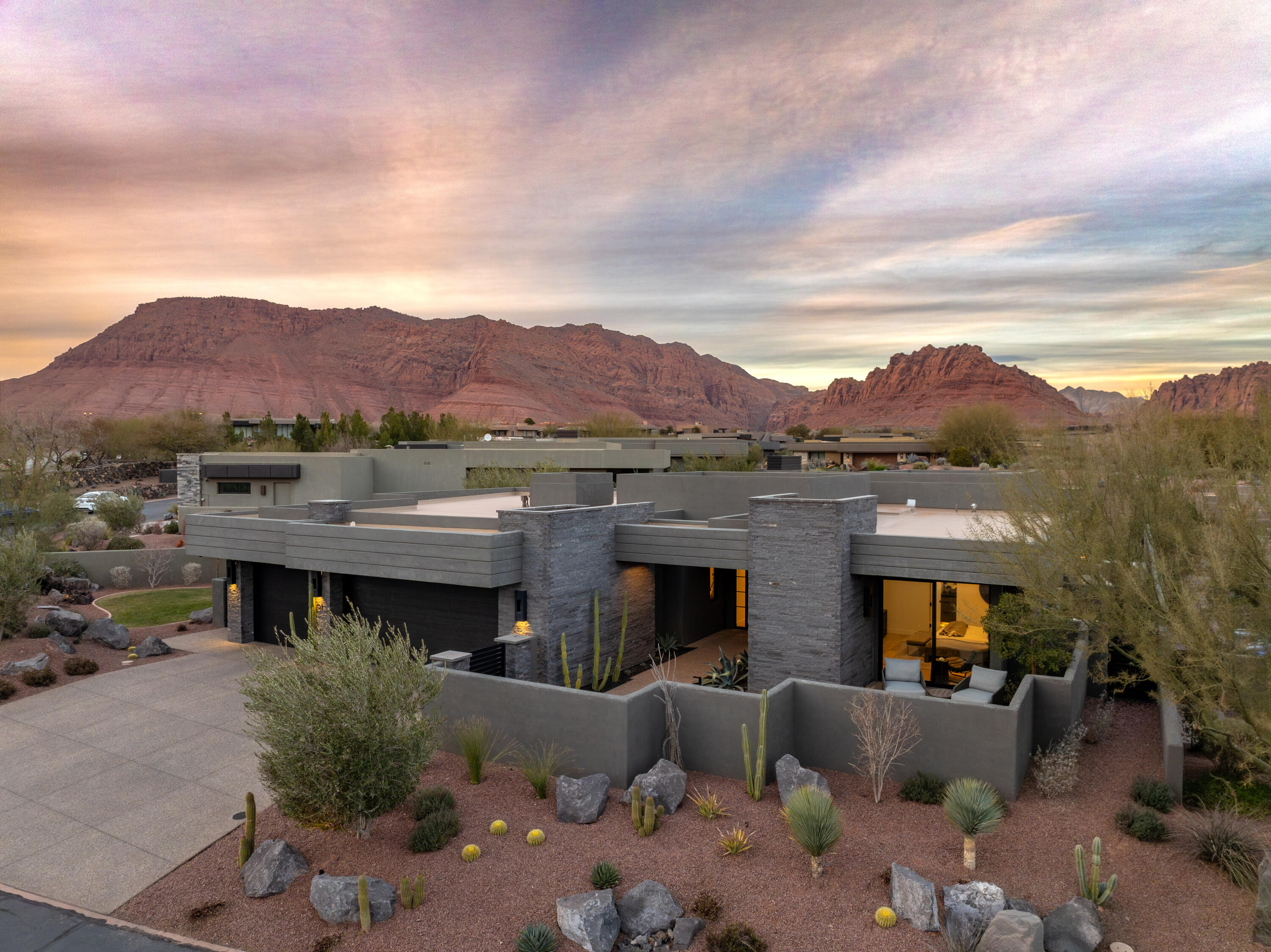 Perched within The Reserve at Entrada, this modern luxury residence is a masterclass in elevated desert living—where architectural precision meets breathtaking natural beauty. Framed by expansive views of Snow Canyon State Park and Red Mountain, the home captures the drama of red rock cliffs and ever-changing desert skies from nearly every angle.
Designed for both refined entertaining and effortless everyday living, the residence offers three private en-suite bedrooms, complemented by a sophisticated powder bath for guests. Clean modern lines and thoughtfully curated finishes create a serene yet striking interior environment.
At the heart of the home, a chef's kitchen showcases Wolf and Sub-Zero appliances, seamlessly blending performance with design. Indoors flows effortlessly outdoors to a fully appointed Lynx outdoor kitchen, ideal for sunset dinners and evening gatherings under the desert sky. The experience continues with an oversized jacuzzi featuring a shamu shelf, perfectly positioned for relaxation and entertaining.
This home is fully equipped with whole-home automation and integrated sound, delivering intuitive control and immersive ambiance throughout. Ascend to the rooftop deck for sweeping panoramic sceneryan exceptional space for entertaining, stargazing, or quiet moments above it all.
Completing the offering, the residence is professionally designed and fully furnished by Restoration Hardware, providing a truly turn-key lifestyle where every detail has been curated to the highest standard.