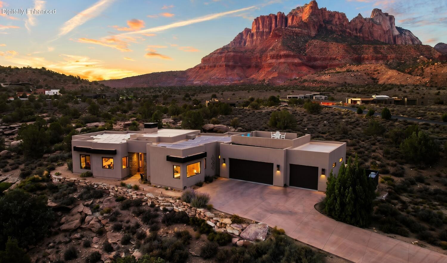 Incredible custom home built and designed by renowned Zion Canyon builder Mark Fahrenkamp, with intentional details specifically designed to enhance privacy and views. Anasazi Plateau is Springdale's premier community -- set on over nearly 300 acres with only 77 homesites, meaning generous open space between homes. Set above the valley floor and away from tourist congestion, this spectacular oversized 0.77-acre lot leaves plenty of room to build an accessory dwelling. Built in 2017, the 4-bed, 3-bath home offers direct sightlines to West Temple, Mt. Kinesava, Eagle Crags, and the cliffs that define the gateway to Zion National Park. Inside, the Great Room opens to 13-foot vaulted ceilings, polished concrete floors, tall Alder doors, and cherrywood cabinetry -- finishes chosen for durability as much as design. A gas fireplace warms the space through the cooler shoulder seasons. The kitchen is built for the way people entertain: Wolf appliances, Sub-Zero refrigeration, and leathered granite countertops that hold up to real use. The primary suite faces Mt. Kinesava directly, with a steam shower, dual heads, and a custom walk-in closet system. A second ensuite keeps guests comfortable, while the remaining bedroom and a dedicated office overlook the cliffs and natural wash below. Outdoor living is where this lot earns its premium. The 1,176 sq ft patio is shaded and oriented for long Springdale evenings, anchored by a firepit, a Bullfrog hot tub, and an Endless Pools Swim Spa. The rooftop deck delivers a full 360° vantage -- sunsets across the canyon, storm fronts moving along the cliffs, and canyon wildlife passing through at the natural pace of the high desert. On the practical side: 50 solar panels keep utility costs low, the 1,144 sq ft three-car attached garage handles the gear that comes with living this close to the park, and all major appliances convey. Trailheads, the Zion shuttle stop, and Springdale's restaurant corridor are minutes from the door. Homes in Anasazi Plateau don't come around often. This one shows what's possible when they do.