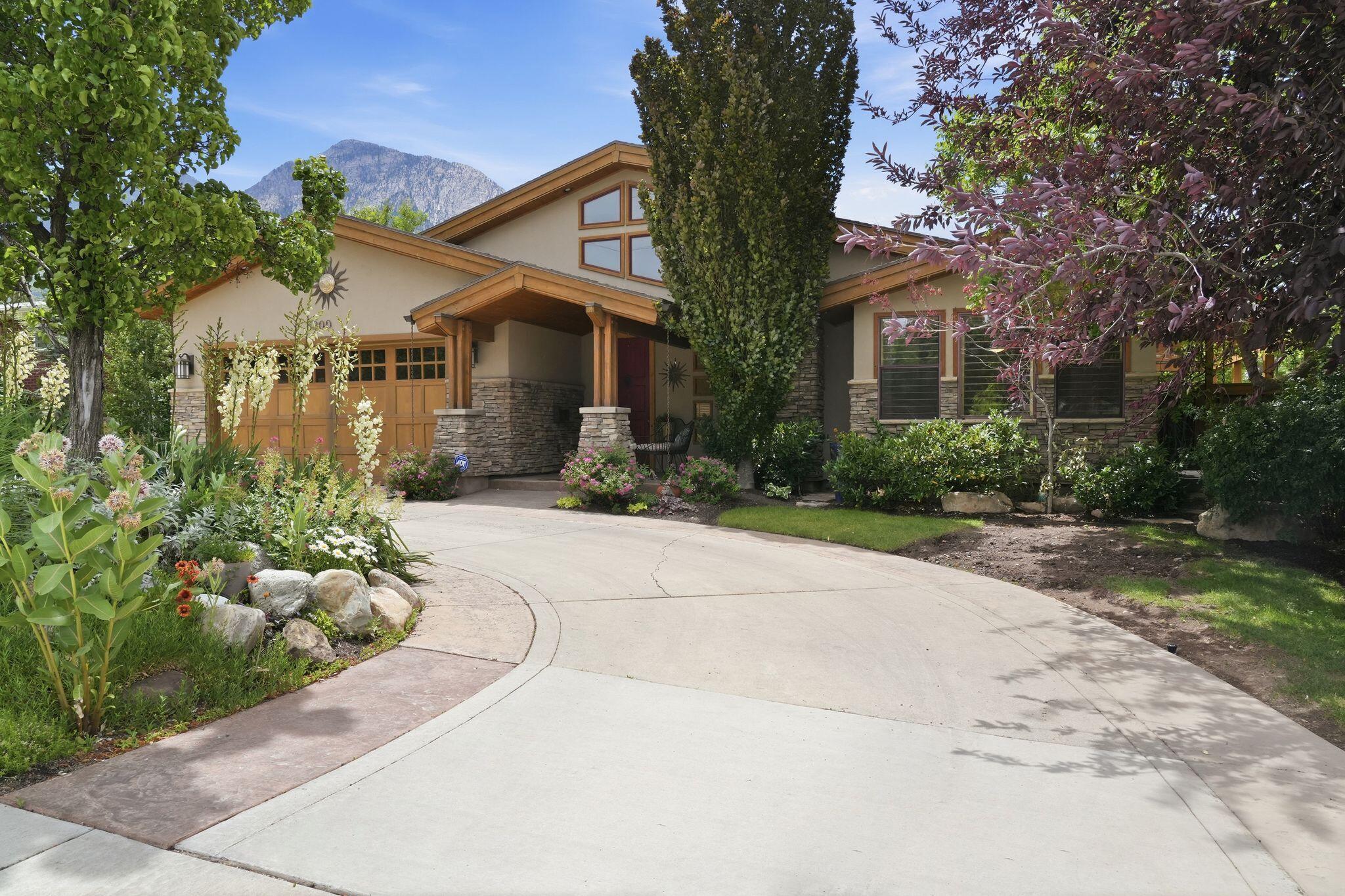 A truly distinctive residence where timeless architecture and modern design come together seamlessly. From the moment you step inside, soaring vaulted ceilings, expansive skylights, and stunning natural stone elements create an inviting atmosphere filled with warmth and character. Extensively remodeled and expanded in 2007, the home offers an open-concept layout centered around a beautifully appointed kitchen featuring a large island, granite countertops, a gas range, and a cozy gas fireplace. The flexible floor plan includes two spacious primary suites-one on the main level and one upstairs-making it ideal for multi-generational living, guests, or a variety of lifestyle needs. The home can also be easily converted into a four-bedroom residence. Designed for entertaining, the lower level features a wet bar and walkout access to a private backyard retreat. Take in spectacular views of Mount Olympus and the valley while enjoying the Trex deck, hot tub, raised garden beds, and mature landscaping that provide exceptional privacy and tranquility. Additional highlights include a fully fenced yard, abundant parking, and a convenient circular driveway. Approved by the city for short-term rental use, this one-of-a-kind property offers an extraordinary opportunity as either a private residence or investment property. Homes with this level of character, flexibility, and setting are rarely available