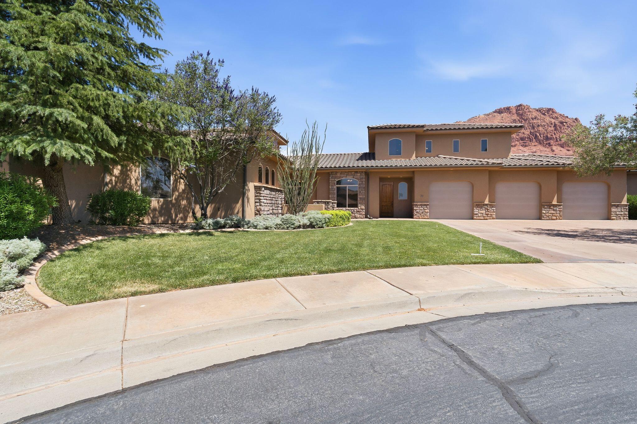 Located at the end of a quiet cul-de-sac in Ivins, this beautiful custom home stands out with its grand, castle-like feel. A large front courtyard guides you inside to an open great room with high ceilings, a gas fireplace, built-in entertainment center, and easily flows into the dining area and kitchen. The kitchen features a large island, stainless steel appliances, prep sink, and double ovens.
The private primary suite sits in its own wing of the home and includes a bonus space perfect for an gym, nursery, or craft room. The bathroom offers dual vanities, a separate tub and shower, and an oversized walk-in closet.
Two additional bedrooms are located on the opposite side of the home for added privacy along with the  oversized laundry and mud room leading to the massive 3.5-car garage.
Upstairs is a fully functional casita with its own entrance, kitchen, living room, bedroom, bathroom, and laundry, perfect for guests or rental income.
Xeriscaped sideyard provides room for RV parking and/or a future pool.