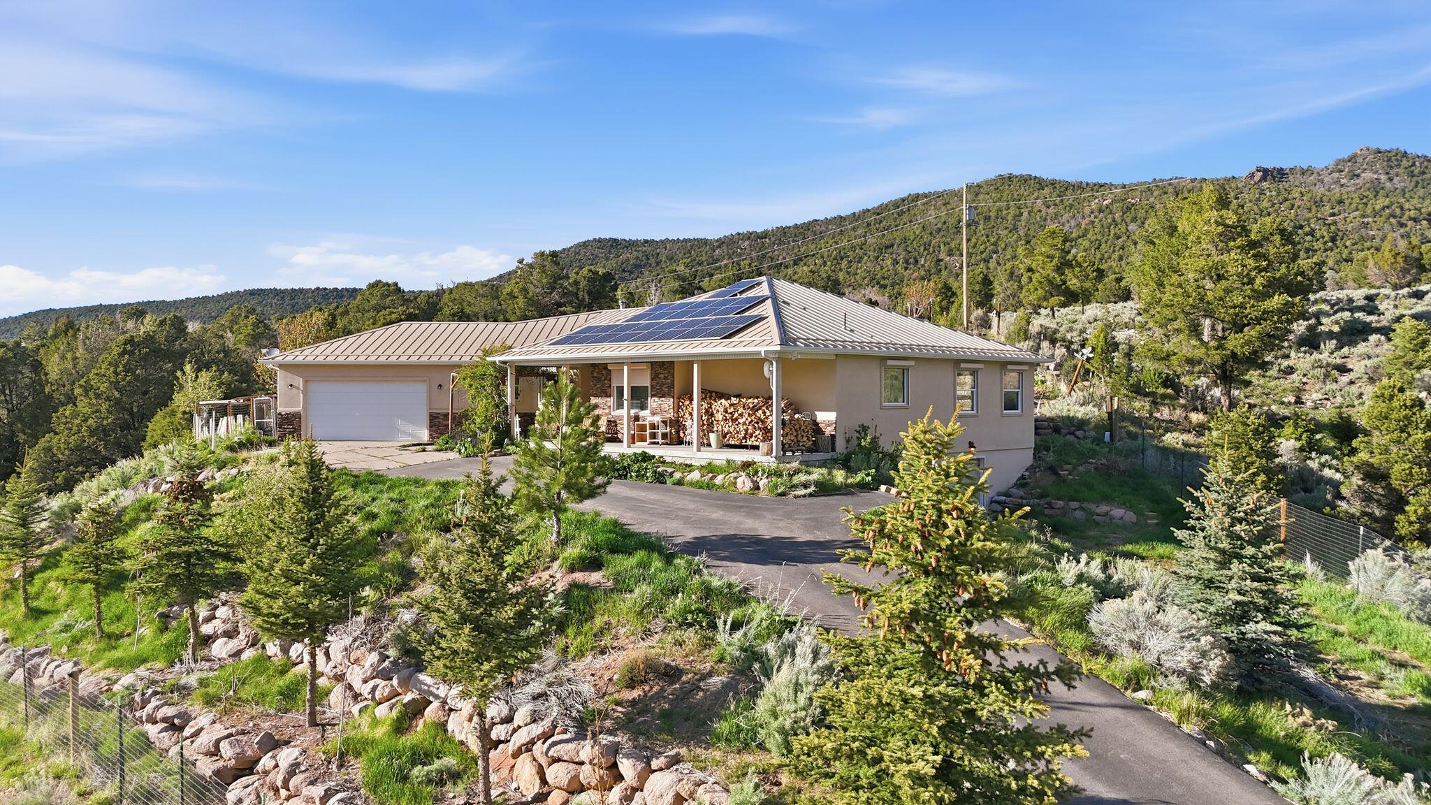Tucked at the end of a private road in scenic Pine Valley, this one-of-a-kind 1.05-acre property offers unmatched privacy, direct bordering access to Forest Service land, and breathtaking 180-degree views of the Pine Valley mountains and Santa Clara River. Built in 2010, this well-crafted two-level home features 2,622 sq ft on the main level with an additional 1,510 sq ft basement, providing ample space and future potential.
Designed with self-sufficiency and rural living in mind, the property includes solar panels with Tesla backup battery storage, a greenhouse, chicken coop, enclosed garden area with raised beds, and a variety of fruit trees. The property is fully fenced, offering flexibility for animals and outdoor use.

Inside, you'll find a warm and inviting layout highlighted by a beautiful sunroom, a cozy wood-burning stove, and large windows that capture the incredible surrounding views. The unfinished basement includes garage door access and is spacious enough to accommodate a side-by-side, offering flexibility for storage, recreation, or future expansion.

Exterior features include durable stucco siding, a metal roof, and roll-down metal security blinds for added protection and peace of mind. The property also includes security cameras and offers direct access to nearby hiking, horseback, and riding trails right from your gate.

If you're looking for a private, off-grid-capable retreat with unbeatable views and direct access to nature, this Pine Valley property is truly a rare find. Home Video Link: https://listings.griffinmarketingagency.com/video/aHaYpAWKmwfg4mlB2G017iFVbP02pUPAfbdr00kgiRWCe4