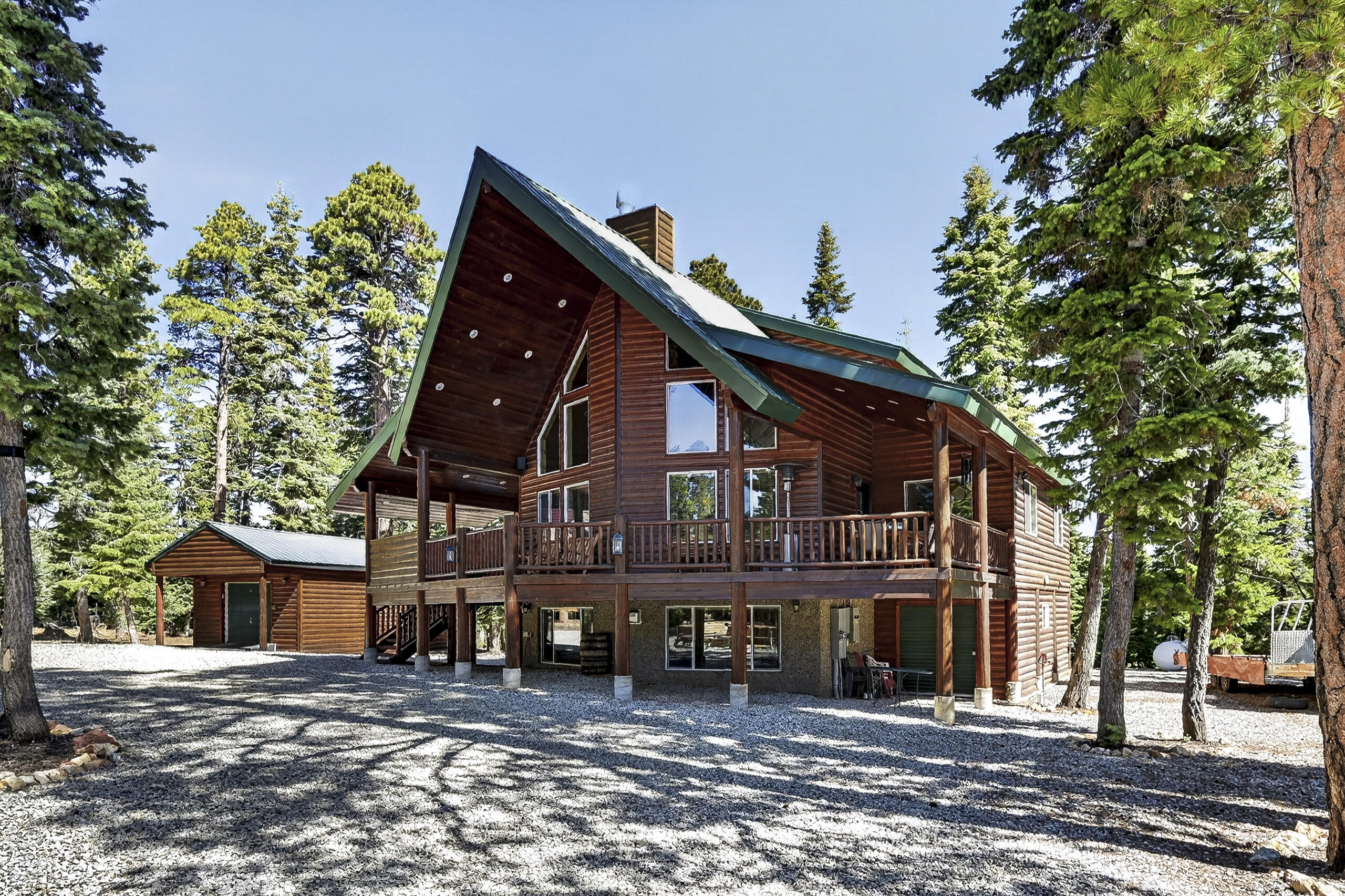 Located in the desirable Meadow View Heights subdivision, this impressive mountain retreat sits on .54 acres and offers 3,198 sq ft with 5 bedrooms, multiple living spaces, and incredible indoor and outdoor entertaining areas. The inviting entrance welcomes you into a warm cabin feel with beautiful tongue and groove finishes, vaulted ceilings, and large windows that bring in natural light throughout. The spacious great room features a stunning rock fireplace and dry bar that flows into the kitchen and dining area complete with a walk-in pantry and plenty of room for gathering. The loft area is currently used as an office but offers flexibility for additional sleeping space, a game area, or whatever fits your needs. The primary suite includes its own rock fireplace, private deck access, dual vanities, a separate tub and shower, and a spacious layout perfect for relaxing after a day on the mountain. The main level laundry room offers additional cabinets, shelving, a sink area, and extra storage space. The lower level offers an ideal entertainment setup with another large family room, a rock fireplace, a dry bar area, and plenty of room for guests and gatherings. Outside, enjoy the covered deck with a built-in BBQ and outdoor kitchen area overlooking the trees, plus a custom firepit area with surrounding benches perfect for evenings in Duck Creek. The property also includes an oversized detached 2-car garage with high ceilings, upper storage area, and an energy-efficient mini-split system providing both heating and cooling, along with an additional outbuilding/workshop ideal for ATVs, toys, and extra storage. Additional property features include a newer Generac whole-home generator with automatic transfer switching, an upsized propane tank, full RV hook-ups, a Kinetico water softener system, and a reverse osmosis water filtration system. Located in a great area close to year-round recreation, trails, and all Duck Creek has to offer. Some furnishings, electronics, appliances, ATVs and snowmobiles are negotiable upon acceptable offer.